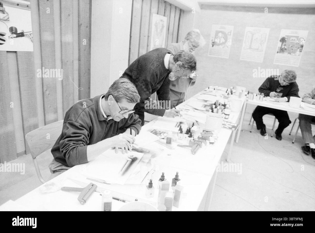 Corso aerografo presso Muys, Whizgle News, Dutch Desk, Paesi Bassi, 1950 - 2000 al 25-11-1990. Questi sono gli elementi dell'immagine. In uno spazio interno ben illuminato, un gruppo di quattro persone è impegnato in un'attività creativa mirata. La camera presenta pareti di legno chiaro che le donano un'atmosfera calda e invitante. La luce naturale si diffonde dall'alto, migliorando la nitidezza della scena. Al centro della composizione si trova un lungo tavolo rettangolare ricoperto di vari materiali artistici. Flaconi di vernice dai colori vivaci, rossi, blu, gialli e verdi, sono disposti accanto a pennelli di diverse dimensioni A. Foto Stock