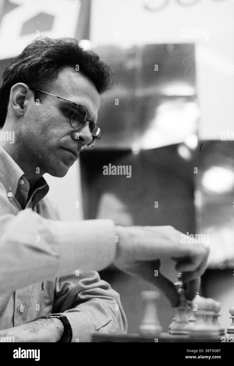 Misc. HST Kampon@ano Timman v.d. Star, Whizgle News, Dutch Desk, Paesi Bassi, 1950 - 2000 il 15-01-1994. L'immagine contiene questi argomenti. Nella scena, un uomo con capelli scuri e leggermente ruvidi è impegnato in una partita a scacchi. Indossa una camicia di colore chiaro con colletto, che contrasta delicatamente con lo sfondo scuro che suggerisce un ambiente competitivo. Il suo sguardo è incentrato sulla scacchiera, suggerendo una profonda concentrazione e un pensiero strategico. I pezzi degli scacchi sul tabellone sono pronti a metà partita, con un mix di pezzi chiari e scuri in varie posizioni. La mano di quell'uomo lo e' Foto Stock