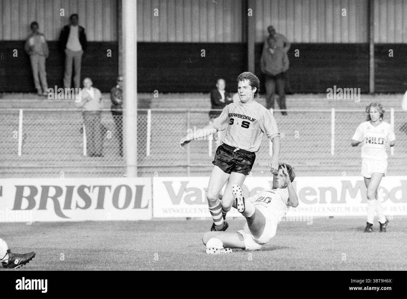 Football Telstar - ADO'20 Football Telstar, Whizgle News, Dutch Desk, Paesi Bassi, 1950 - 2000 il 04-08-1988. Questi sono gli elementi dell'immagine. La scena cattura un momento dinamico su un campo da calcio. In primo piano, due giocatori dominano la messa a fuoco. Uno indossa una maglia scura, numerata 9, e sembra essere in movimento, manovrando abilmente la palla. Ha un'espressione determinata, suggerendo un coinvolgimento attivo nello spettacolo. Il giocatore avversario, vestito con una maglia leggera, sta scivolando a terra, tentando di intercettare la palla, che si trova proprio di fronte a lui. La sua postura Foto Stock