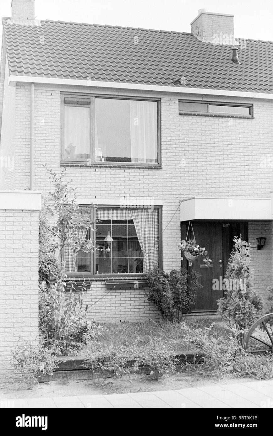 Est. Van Graan contro Visch 15411 dove sono stati stampati dollari contraffatti esterno, Whizgle News, Dutch Desk, Paesi Bassi, 1950 - 2000 il 08-09-1975. L'immagine include questi argomenti. La scena raffigura una casa a due piani caratterizzata dalla sua facciata in mattoni di colore chiaro e da un tetto con tegole rosse. La parte anteriore della casa presenta una porta di legno in posizione centrale, incorniciata da una modesta area porticata. Alcune piante in vaso e arbusti sono visibili lungo la base della casa, suggerendo un sottile paesaggio che aggiunge un tocco di verde all'ambiente. Al piano terra, c'è una finestra con tende bianche semi-trasparenti Foto Stock