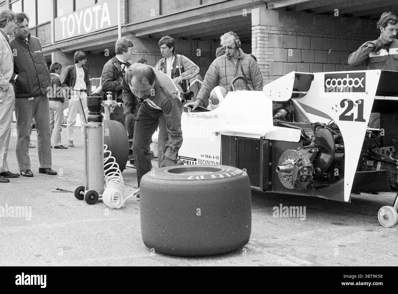 La pit Lane del circuito di Zandvoort Zandvoort, Whizgle News, Dutch Desk, Paesi Bassi, 1950 - 2000 il 27-07-1984. Questi argomenti vengono visualizzati nell'immagine. La scena cattura una vivace area di sport motoristici piena di attività e anticipazione. Da un lato, un'elegante auto da corsa, formidabile nel suo design, è posizionata in modo prominente. La sua carrozzeria, verniciata in una straordinaria combinazione di bianco e rosso, presenta distintivi loghi dello sponsor, che ne fanno un accenno allo spirito competitivo. Gli pneumatici della vettura sono notevolmente grandi e robusti, enfatizzando la potenza e la velocità. In primo piano, un membro della squadra, vestito con una tuta scura, Foto Stock