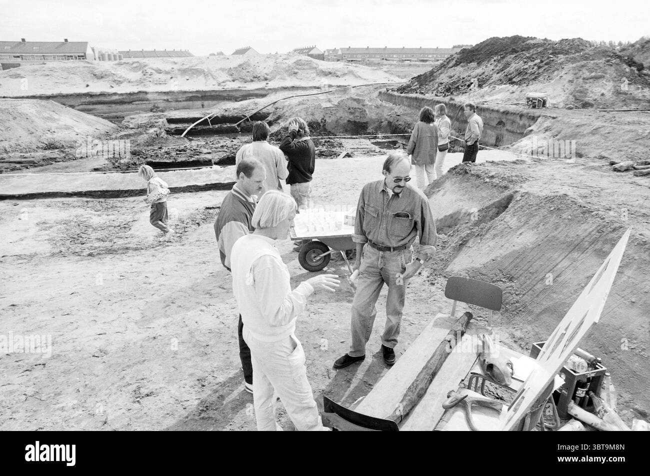 Scavi Velserbroek, Whizgle News, Dutch Desk, Paesi Bassi, 1950 - 2000 su 11-09-1992. Questi sono gli argomenti nell'immagine. In un sito di scavo sabbioso, un gruppo di individui è sparso intorno, impegnati in varie attività legate allo scavo. Il paesaggio è dominato dalla terra grezza, con una grande fossa che rivela strati di terreno e roccia. Diversi adulti sono riuniti in stretta conversazione, gestendo animatamente. Una persona è vestita con un vestito di colore chiaro, alzate le mani come se spiegasse qualcosa di importante, mentre un'altra ascolta con attenzione, indossando una camicia scura e occhiali. Nelle vicinanze c'è un bambino Foto Stock
