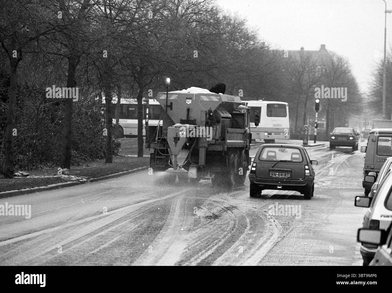 IJzel Parklaan Haarlem Parklaan Paesi Bassi, Whizgle News, Dutch Desk, Paesi Bassi, 1950 - 2000 il 29-11-1993. L'immagine mostra questi argomenti. La scena cattura un ambiente urbano invernale caratterizzato da una tavolozza di grigi e bianchi che evoca un'atmosfera cupa ma serena. La neve ricopre il terreno, ammorbidendo i contorni dell'asfalto lasciando macchie di strada buia e esposta in luoghi in cui il traffico ha disturbato il gelo. Su un lato della strada, un grande spazzaneve industriale è centrale per la composizione, la sua struttura robusta e funzionale. Si è visto liberare la neve Foto Stock