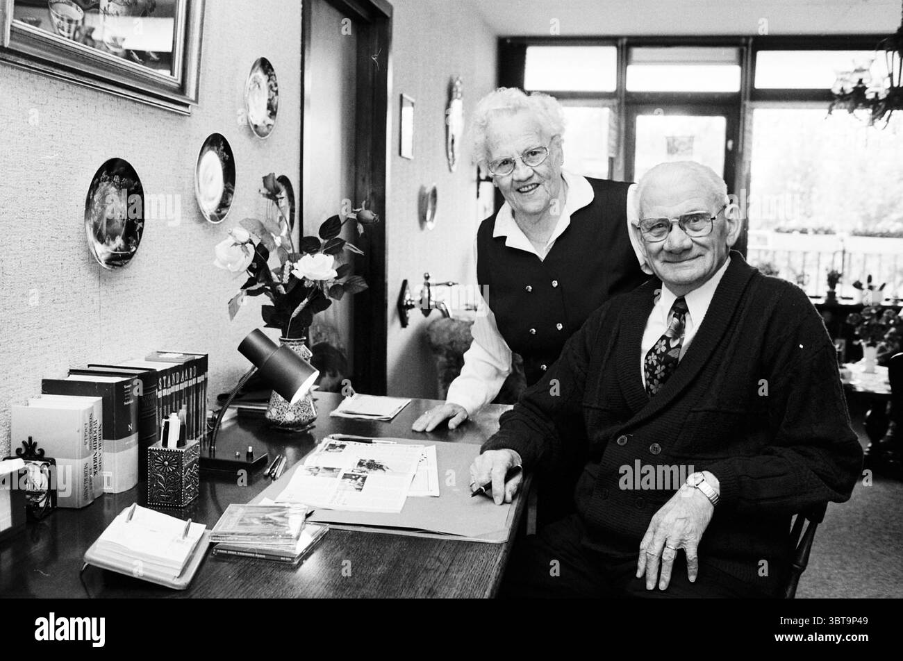 La famiglia Zijlstra si è sposata per 60 anni Nieuw-Vennep Nieuw-Vennep, Whizgle News, Dutch Desk, Paesi Bassi, 1950 - 2000 il 18-10-1995. L'immagine include questi argomenti. In un interno molto illuminato, due persone anziane sono posizionate su una scrivania in legno, adornata con vari oggetti personali. La scena trasmette un senso di intimità e nostalgia. A sinistra, una donna con i capelli bianchi, con un taglio pulito, indossa un gilet nero su una camicetta bianca. Il suo sorriso caldo trasuda cordialità e i suoi occhiali le amplificano leggermente gli occhi, attirando l'attenzione sulla sua espressione allegra. Accanto a lei, un uomo con una Foto Stock