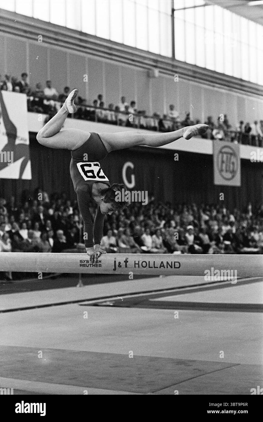 European Artistic Gymnastics Championships Amsterdam ?67 Gymnastics, Whizgle News, Dutch Desk, Paesi Bassi, 1950 - 2000 il 28-05-1967. Questi sono gli argomenti nell'immagine. La scena cattura un momento dinamico in una competizione di ginnastica, mostrando una ginnasta che esegue una routine abile sul raggio di bilanciamento. L'atleta è vestita con un corpo vibrante che contrasta sorprendentemente con i toni tenui dell'ambiente circostante, sottolineandone la forma e l'atleticità. Il suo corpo è ben posizionato, con una gamba allungata in alto sopra la testa, mentre l'altra è piegata, dimostrando sia agilità che balanc Foto Stock