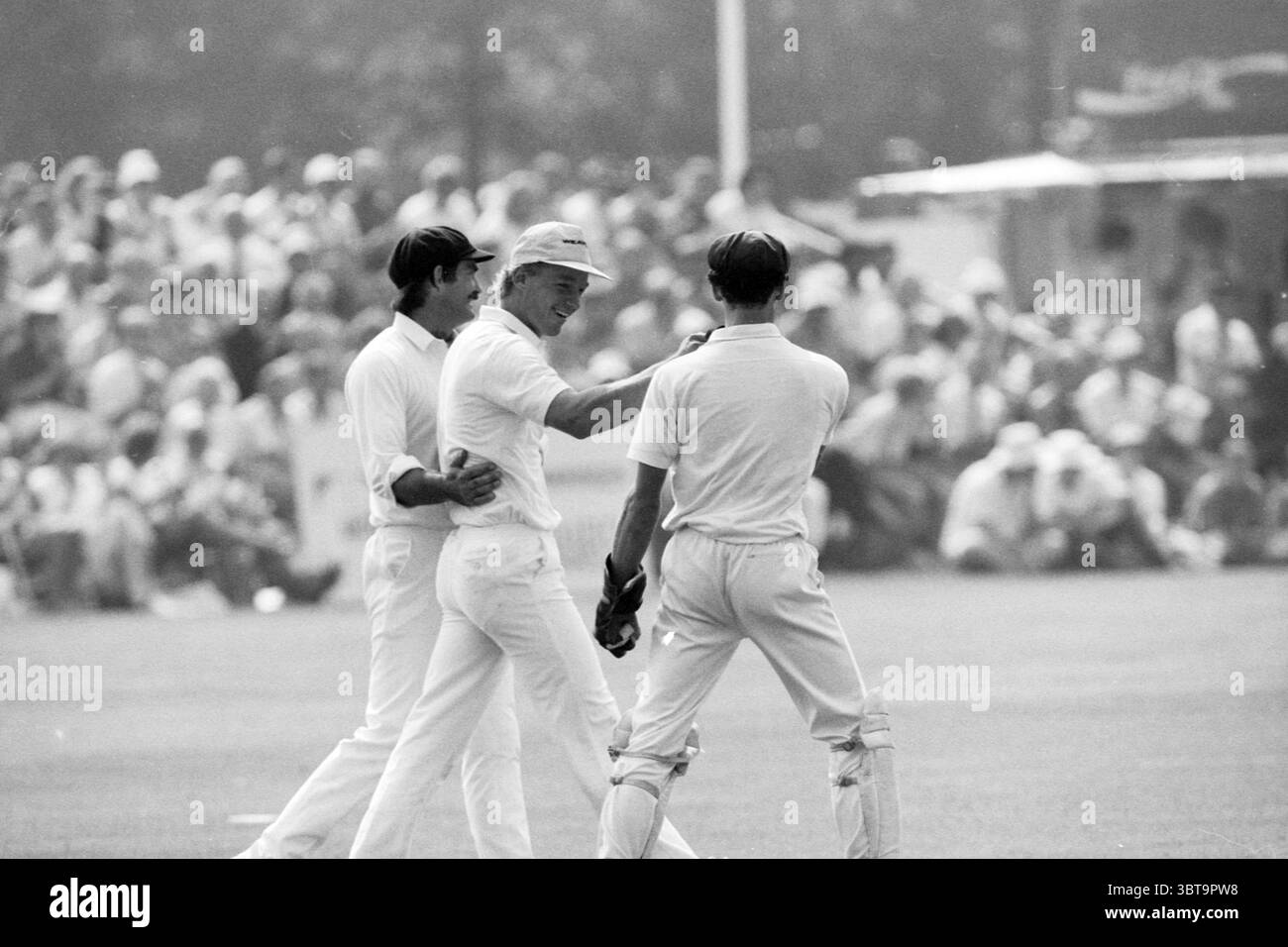 Cricket Paesi Bassi-Indie occidentali, Whizgle News, Dutch Desk, Paesi Bassi, 1950 - 2000 il 14-08-1991. Questi argomenti vengono visualizzati nell'immagine. In un ambiente dinamico all'aperto, tre personaggi maschili sono impegnati in una vivace interazione mentre indossano abiti da cricket tradizionali, uniformi bianche complete di berretti. Gli individui mostrano una serie di espressioni; una sorride in generale, segnalando cameratismo ed entusiasmo, mentre le altre mostrano reazioni diverse, forse divertimento o concentrazione. Sullo sfondo, si vede una folla, composta da numerosi spettatori, che danno un senso di scala ed energia alla Foto Stock