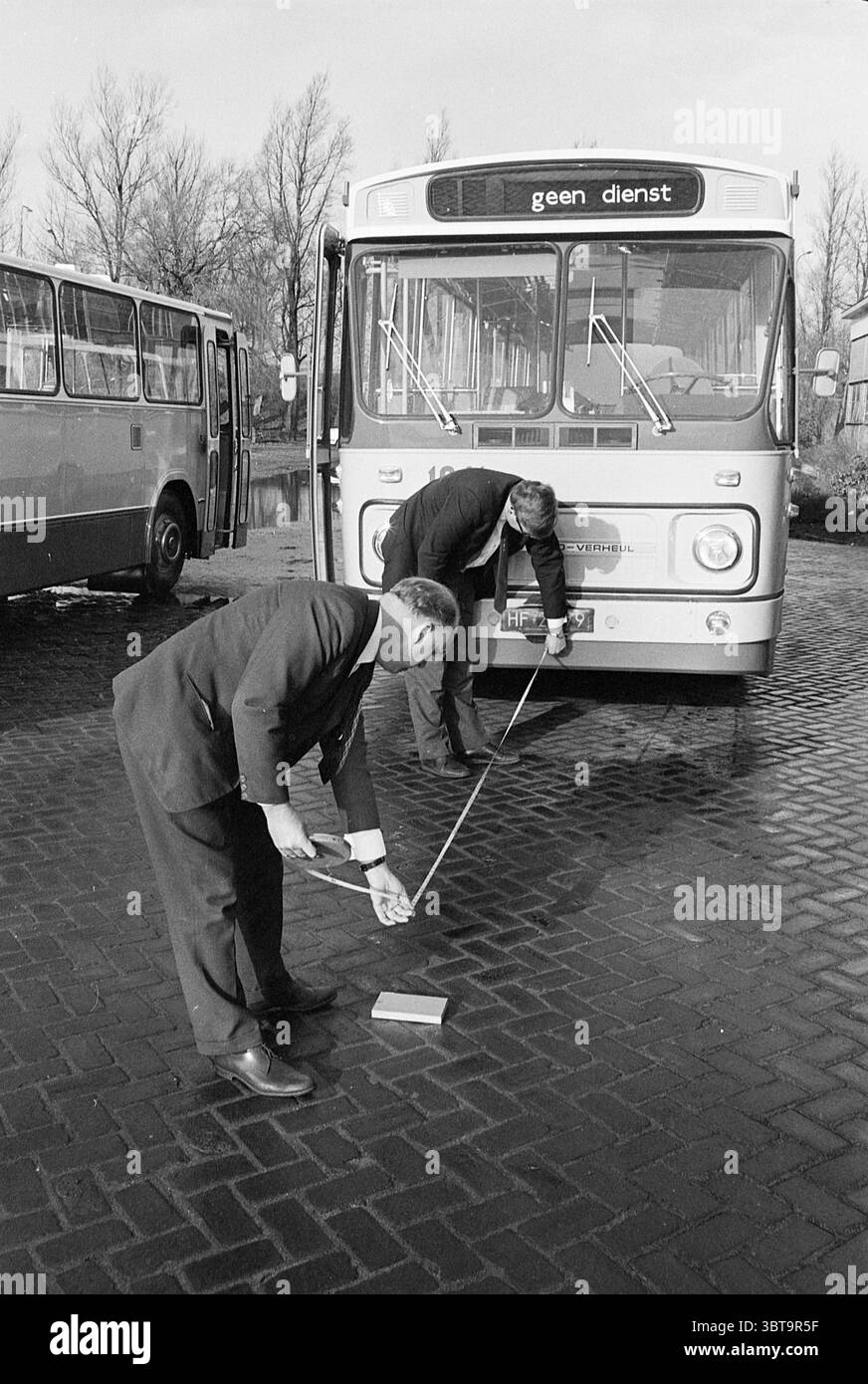 Road test bus 1041 Noord Zuid Hollandse Vervoersmaatschappij N.V. NZ Verheul Carosseriefabriek Waddinxveen, Whizgle News, Dutch Desk, Paesi Bassi, 1950 - 2000 il 24-01-1968. Questi sono gli elementi dell'immagine. La scena è ambientata in un'area industriale, probabilmente un deposito di autobus o un cantiere di manutenzione, caratterizzata da una superficie dura e pavimentata. Due uomini sono impegnati in un'attività vicino a un grande autobus fisso. Sono vestiti con un abbigliamento formale, indossando abiti scuri che conferiscono un'aria professionale all'ambiente. L'autobus, che sembra vintage, ha una parte anteriore arrotondata con un ampio parabrezza e il cartello di destinazione DEP Foto Stock