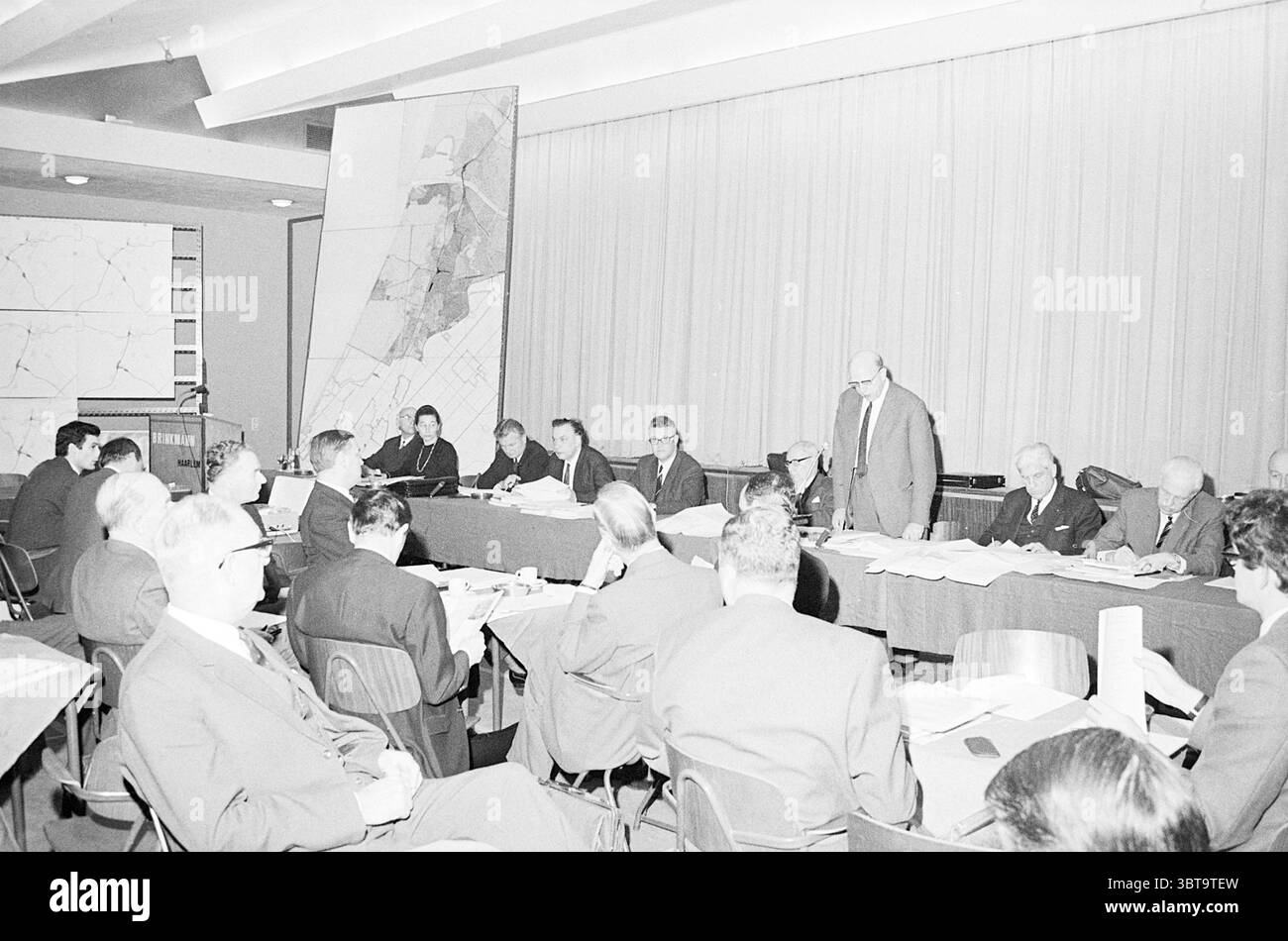 Riunioni del Comitato regionale del piano, Whizgle News, Dutch Desk, Paesi Bassi, 1950-2000, il 30-01-1970. Questi sono gli elementi dell'immagine. La scena è ambientata all'interno di una sala conferenze caratterizzata da un grande tavolo rettangolare che ospita un gruppo di persone coinvolte in una discussione. L'atmosfera suggerisce serietà e formalità. Le persone sono posizionate intorno al tavolo, con alcune sedute e altre in piedi. Il loro abbigliamento è prevalentemente formale, con abiti e cravatte, indicativo di un ambiente professionale. Alcuni uomini sembrano essere in discussione, mentre altri ascoltano intensamente, suggerendo Foto Stock