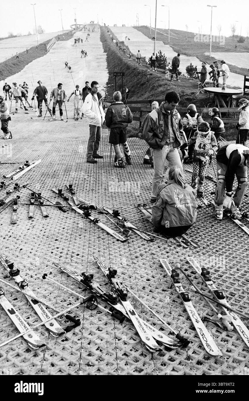 Gara di sci atmosfera Spaarnwoude Spaarnwoude, Whizgle News, Dutch Desk, Paesi Bassi, 1950 - 2000 su 31-10-1997. Questi argomenti sono mostrati nell'immagine. La scena si snoda su una pista da sci artificiale e inclinata, progettata per gli sport invernali. La superficie appare strutturata, con un motivo simile a una griglia per supportare gli sciatori. In primo piano, diverse paia di sci si trovano sparsi, i loro design eleganti mostrano un mix di colori, alcuni rossi e blu brillanti che contrastano con il grigio opaco della pista. Nelle vicinanze, le persone sono impegnate in varie attività: Alcuni indossano l'attrezzatura da sci, ripiano Foto Stock