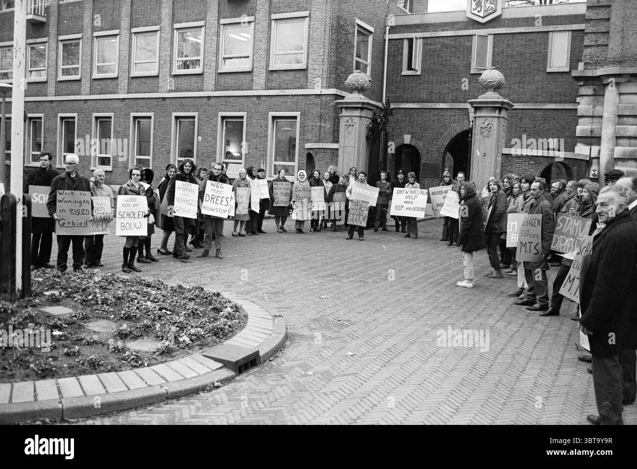 Dimostrazione contro il ministro Drees of Transport Public Works and Water Management riguarda North Holland North presso la Provincial House Haarlem Dreef the Netherlands, Whizgle News, Dutch Desk, Paesi Bassi, 1950 - 2000 il 25-11-1975. Questi sono gli argomenti nell'immagine. Nella scena, un raduno di persone occupa un cortile acciottolato circondato da edifici in mattoni con grandi finestre. L'atmosfera è carica di un senso di attivismo e determinazione. Un gruppo eterogeneo di individui è posizionato in un semicerchio, alcuni con espressioni risolute, mentre altri appaiono più contemplativi Foto Stock