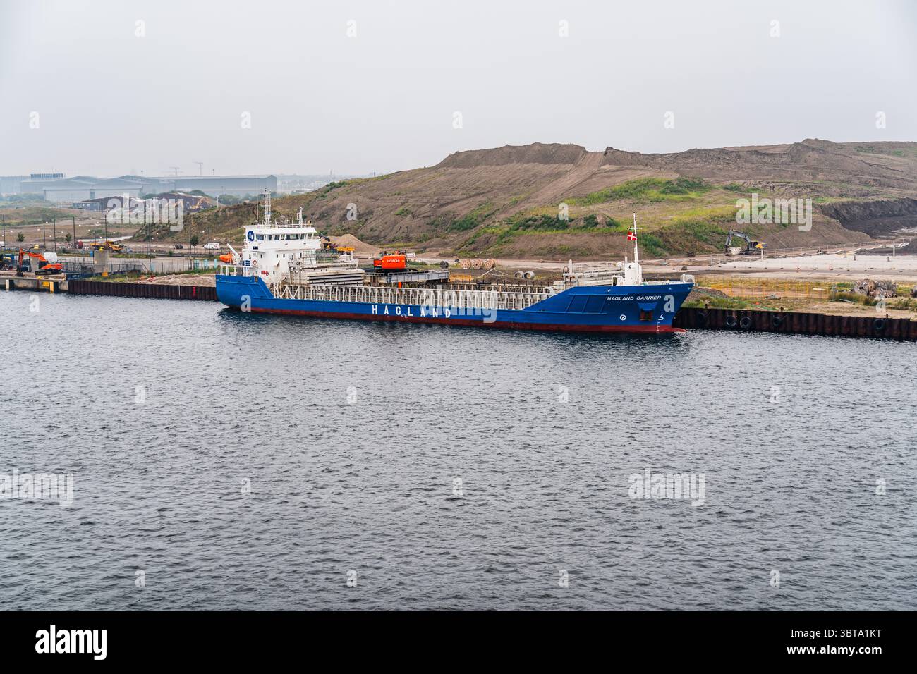 La nave Hagland Carrier scarica sabbia o ghiaia con l'escavatore Hitachi 670, sostenendo progetti di costruzione in corso nel porto di Nordhavn in Danimarca Foto Stock