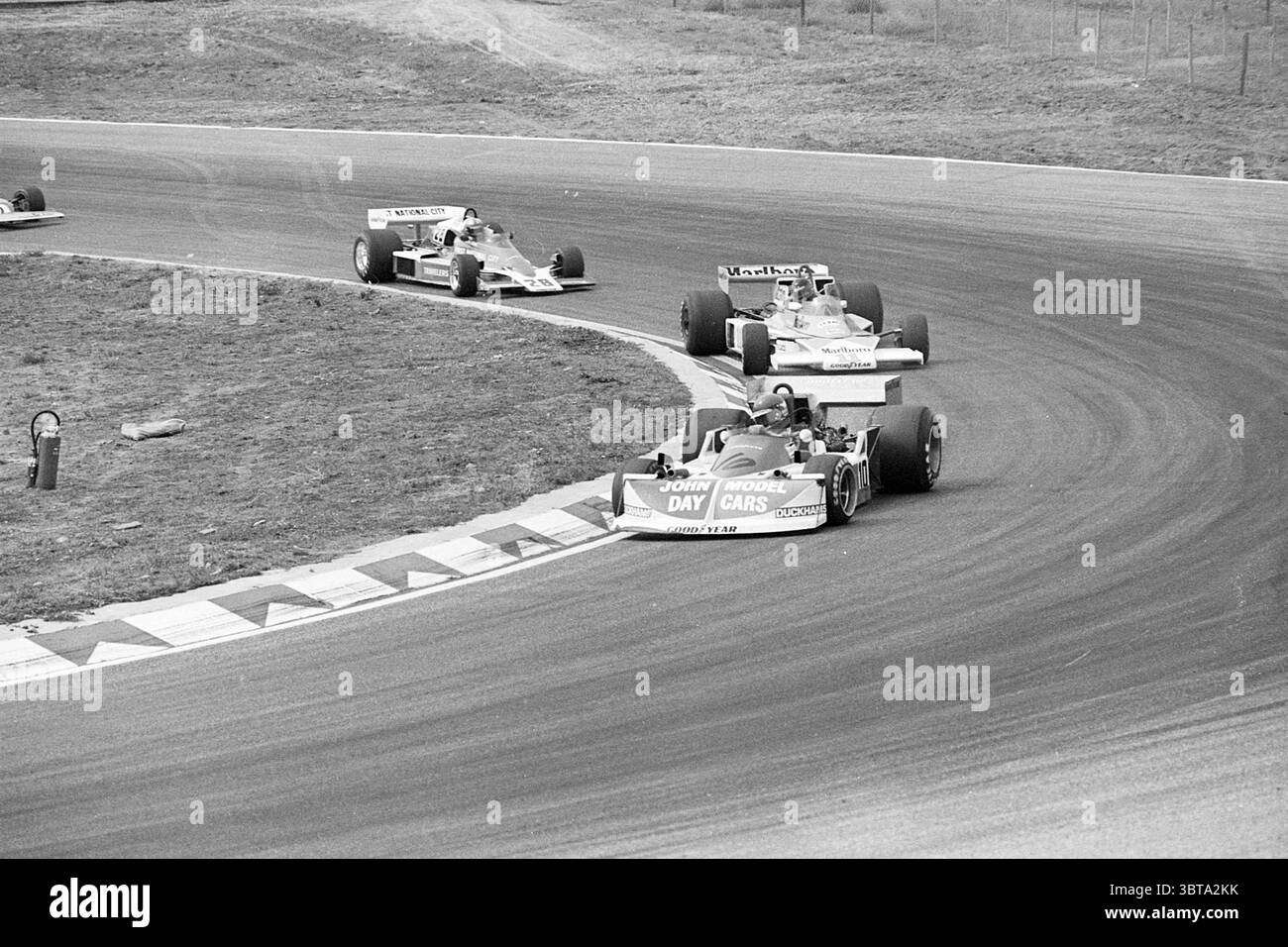 Gare automobilistiche Zandvoort Grand Prix Grand prix, Whizgle News, Dutch Desk, Paesi Bassi, 1950 - 2000 il 29-08-1976. Questi argomenti vengono visualizzati nell'immagine. La scena cattura un momento dinamico di un evento di corse su una pista tortuosa. Tre auto stanno manovrando in una curva stretta, mostrando il loro design elegante. La vettura principale, posizionata in prima linea, presenta una livrea audace con una combinazione di colori, rosso e bianco, con il nome "John Moore" ben visibile sul lato. La sua forma aerodinamica è completata da una carena a basso profilo, che enfatizza velocità e prestazioni. Il seco Foto Stock