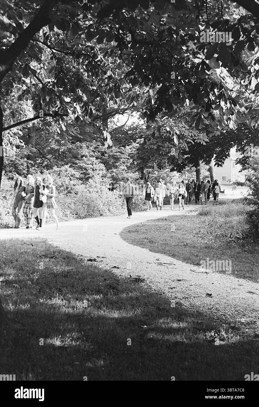 Walking club Club of the Week Walking, Whizgle News, Dutch Desk, Paesi Bassi, 1950 - 2000 il 13-06-1972. Questi argomenti sono mostrati nell'immagine. La scena cattura un percorso tortuoso che si snoda attraverso un lussureggiante ambiente all'aperto. Lungo il percorso ci sono alberi alti, il loro fitto fogliame crea macchie di luce e ombra. Il verde è ricco e variegato, con diverse sfumature di verde che si mescolano, dalle foglie scure sopra alle erbe e piante più leggere al livello del suolo. Lungo il percorso, gruppi di individui possono essere visti camminare in varie direzioni. Alcuni passeggiano piacevolmente, perh Foto Stock