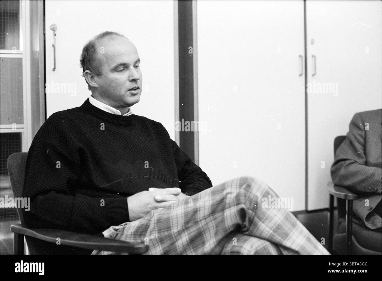 3 signori a KLM A'veen KLM Amstelveen, Whizgle News, Dutch Desk, Paesi Bassi, 1950 - 2000 il 28-09-1989. Questi sono gli argomenti nell'immagine. In un ambiente che evoca un senso di contemplazione accademica, un uomo siede in prima linea, trasmettendo un comportamento rilassato. Indossa un maglione scuro e testurizzato che contrasta dolcemente con i toni chiari dell'ambiente circostante. I suoi pantaloni sono caratterizzati da un motivo a quadri con colori tenui, che creano un equilibrio visivo con il suo abbigliamento superiore. La postura dell'uomo è leggermente slacciata, le mani poggiano ponderatamente in grembo, suggerendo che è in profonda contemplazione o e Foto Stock