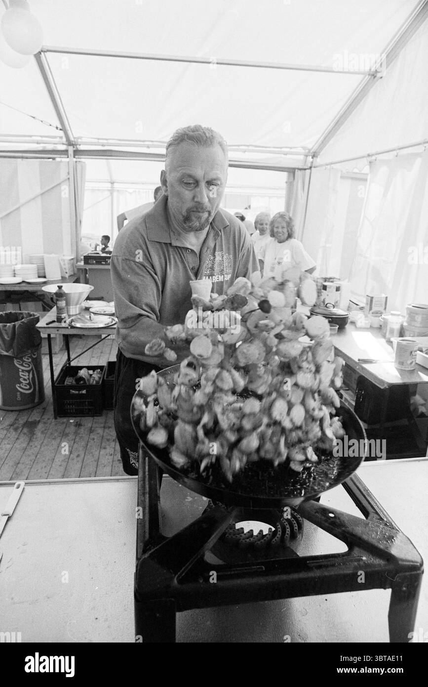 Haarlem Cup The Cook, Whizgle News, Dutch Desk, Paesi Bassi, 1950 - 2000 il 01-08-1995. Questi sono gli elementi dell'immagine. In un ambiente vivace, un individuo sta gettando energicamente una grande porzione di cibo in una padella sopra una fonte di calore. La figura è vestita con una camicia grigia, che mostra un'espressione determinata che indica la concentrazione e l'entusiasmo. La scena è vivace, con molte altre persone sullo sfondo impegnate in varie attività, contribuendo a creare un'atmosfera vivace. La padella trabocca di un mix di ingredienti colorati, forse una combinazione di verdure e frutti di mare, mixi Foto Stock