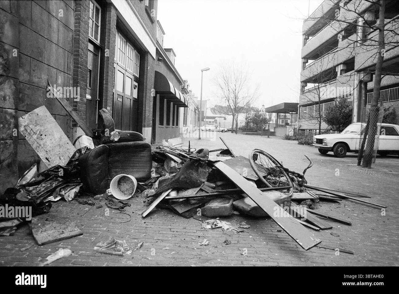 Spazzatura nella spazzatura Haasstraat Haarlem Haasstraat Paesi Bassi, Whizgle News, Dutch Desk, Paesi Bassi, 1950 - 2000 il 02-03-1987. L'immagine include questi argomenti. La scena raffigura un'area urbana caratterizzata da un senso di abbandono e disuso. In primo piano, c'è una grande pila di detriti, tra cui mobili scartati, pneumatici e vari pezzi di metallo di scarto. I materiali appaiono intemprati e pesantemente sporchi, contribuendo a una sensazione generale di abbandono. A sinistra, un edificio con una facciata scura e porte ad arco si erge parzialmente visibile. Le sue sfumature di grigio e AN Foto Stock