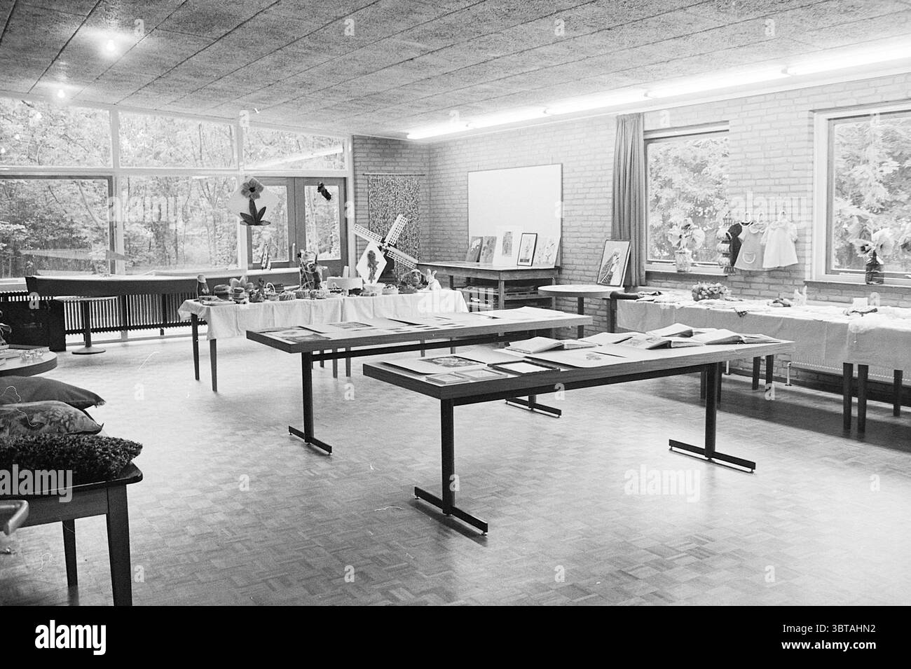 Apertura del padiglione per anziani di Westerhout apertura aperture messe in uso, Whizgle News, Dutch Desk, Paesi Bassi, 1950 - 2000 il 06-09-1968. L'immagine contiene questi argomenti. La scena presenta interni spaziosi, caratterizzati da un design moderno con grandi finestre che invitano alla luce naturale e forniscono uno scorcio di verde all'esterno. Le pareti sono realizzate in mattoni di colore chiaro, che aggiungono calore all'atmosfera, completato da un soffitto testurizzato. In primo piano, diversi tavoli di legno sono ordinatamente disposti, mostrando una serie di oggetti. Le superfici sono adornate con vari oggetti, inclusi Foto Stock