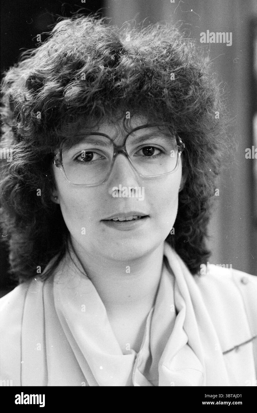 Haarlem Flower Girls as models for eyewear fashion at Federman Haarlem Paesi Bassi, Whizgle News, Dutch Desk, Paesi Bassi, 1950 - 2000 il 21-04-1983. L'immagine include questi argomenti. In questa scena, una donna viene catturata in un ritratto ravvicinato. Ha un'acconciatura distintiva caratterizzata da capelli voluminosi e ricci che incornicia il suo viso. I ricci le conferiscono un aspetto morbido e ruvido. I suoi occhiali da vista sono prominenti, con montature spesse che aggiungono un tocco accademico al suo look. L’espressione della donna è neutrale ma accessibile, suggerendo un senso di calma fiducia. Indossa un blo di colore chiaro Foto Stock