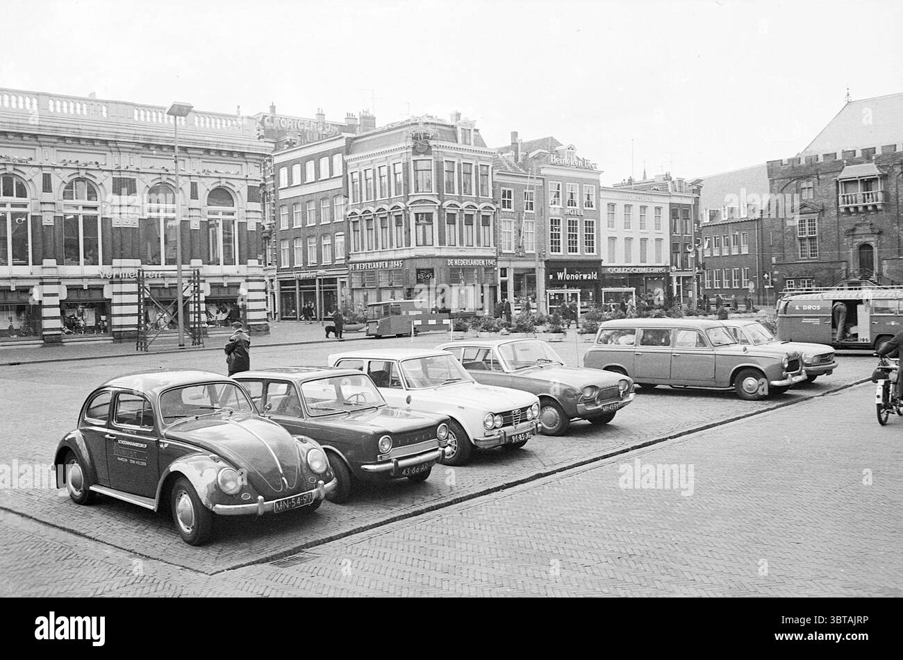 Auto parcheggiate sul Grote Markt guardando verso Grote Houtstraat Haarlem Grote Markt Paesi Bassi, Whizgle News, Dutch Desk, Paesi Bassi, 1950 - 2000 su 11-1969. Questi argomenti sono mostrati nell'immagine. La scena cattura una vivace piazza urbana caratterizzata da una varietà di auto d'epoca parcheggiate in file ordinate. In primo piano c'è un Maggiolino vintage con la sua iconica forma arrotondata, dipinto in contrasto con colori scuri e chiari. Oltre a questo, un mix di altri veicoli classici, caratterizzati da un design distinto di varie epoche, aggiunge un tocco nostalgico alla scena. Le funzioni dello sfondo Foto Stock
