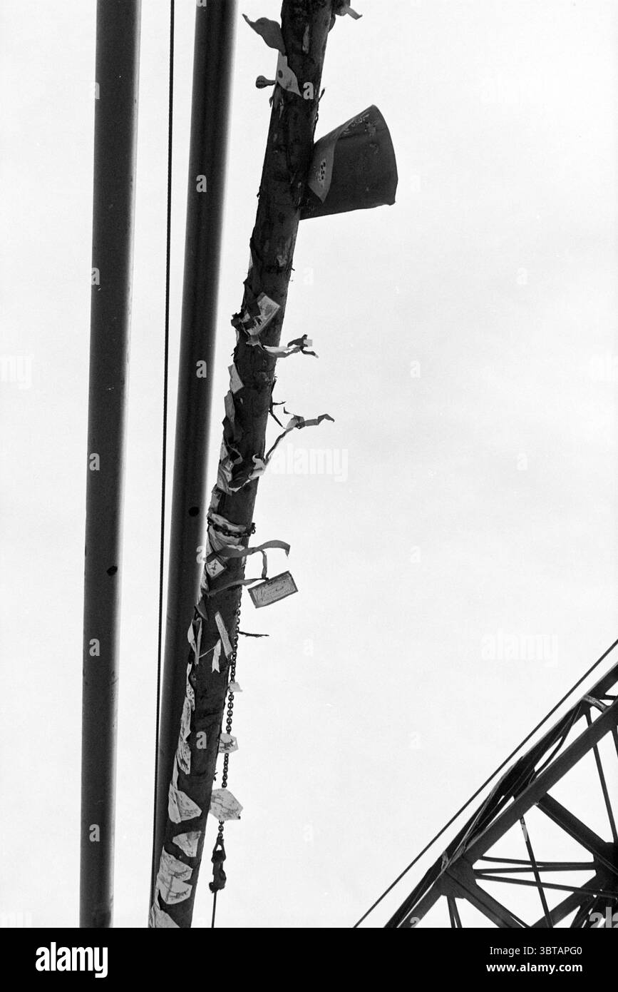 Un gruppo di bambini assiste alla guida di un primo post decorato (P-post) Hillegom, Whizgle News, Dutch Desk, Paesi Bassi, 1950 - 2000 il 16-03-1993. Questi sono gli elementi dell'immagine. La scena cattura una vista orizzontale di una struttura urbana, probabilmente un ponte, vista da un angolo basso. Il primo piano presenta una lunga barra di metallo intemprato, che corre lungo il telaio. Questa trave metallica è decorata con vari oggetti e oggetti personali, tra cui pezzi di tessuto, carta e piccoli gettoni, che indicano una storia di messaggi o ricordi lasciati dagli individui. Sopra il fascio, una coppia di c Foto Stock