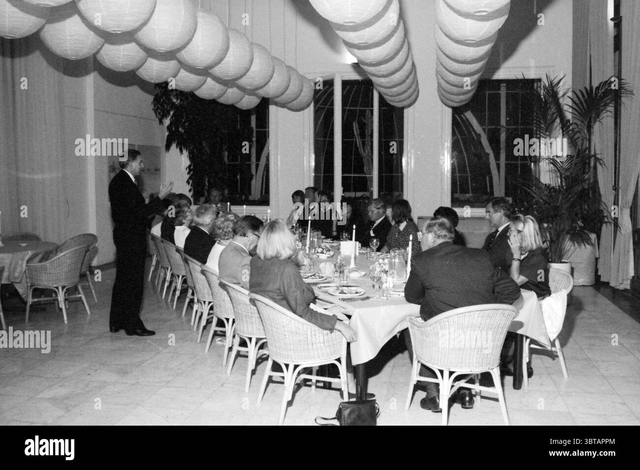 Dinner Orangery Nuts United Savings Banks, Whizgle News, Dutch Desk, Paesi Bassi, 1950 - 2000 il 03-09-1987. L'immagine mostra questi argomenti. In una spaziosa sala da pranzo, l'atmosfera si fonde con un senso di eleganza e formalità. La sala presenta file di tavoli rotondi adornati con tovaglie bianche che si avvolgono elegantemente fino al pavimento. Ogni tavolo e' circondato da sedie in tessuto di colore chiaro che offrono un contrasto rustico ma raffinato con le superfici lisce dei tavoli. Sopra, gruppi di lanterne morbide e sferiche si sgretolano dal soffitto, proiettando un caldo e invitante bagliore in tutto lo spazio Foto Stock