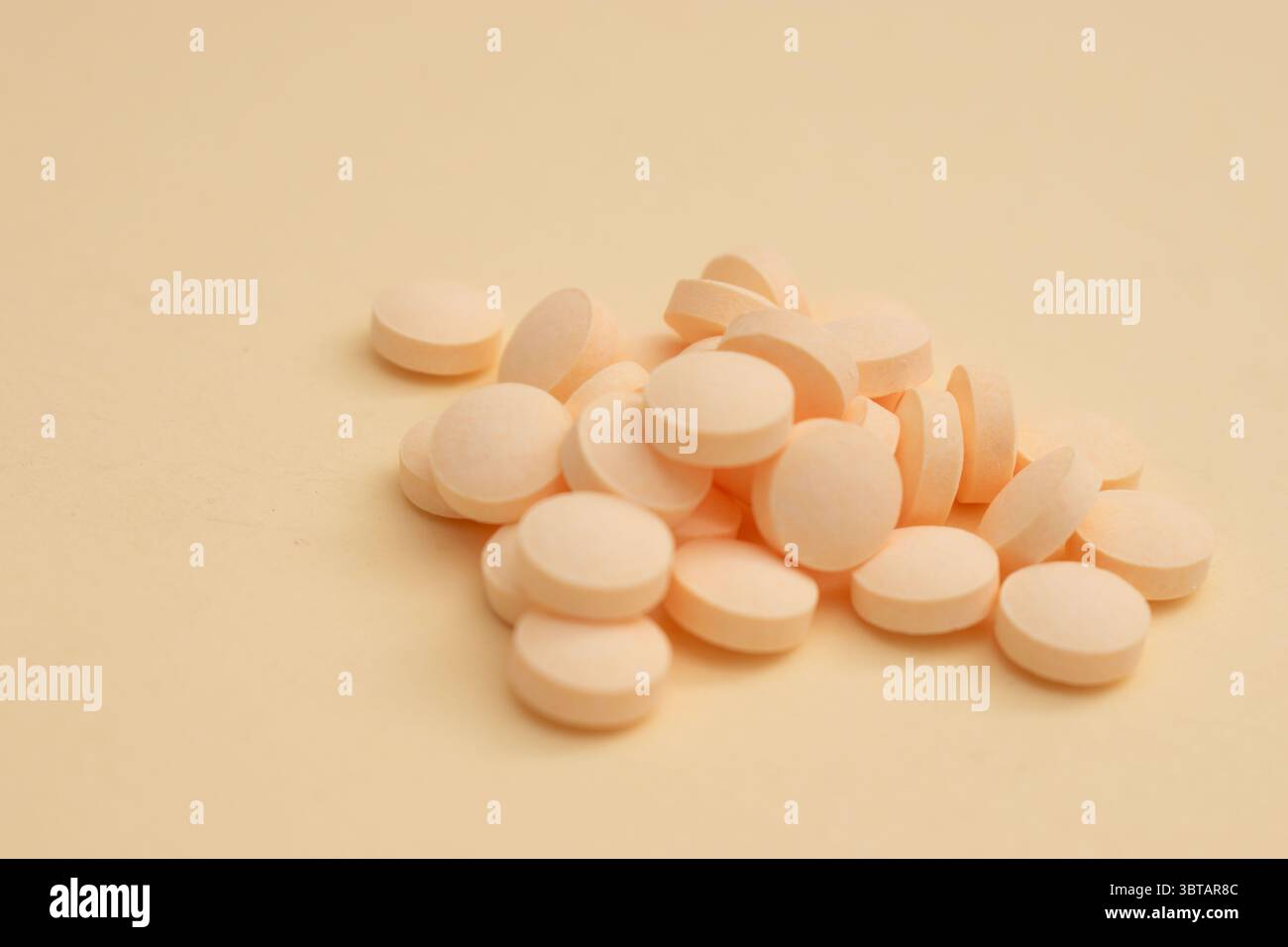 Concetto minimalista con pillole rotonde bianche in contenitore di vetro e cucchiaio su sfondo beige Foto Stock