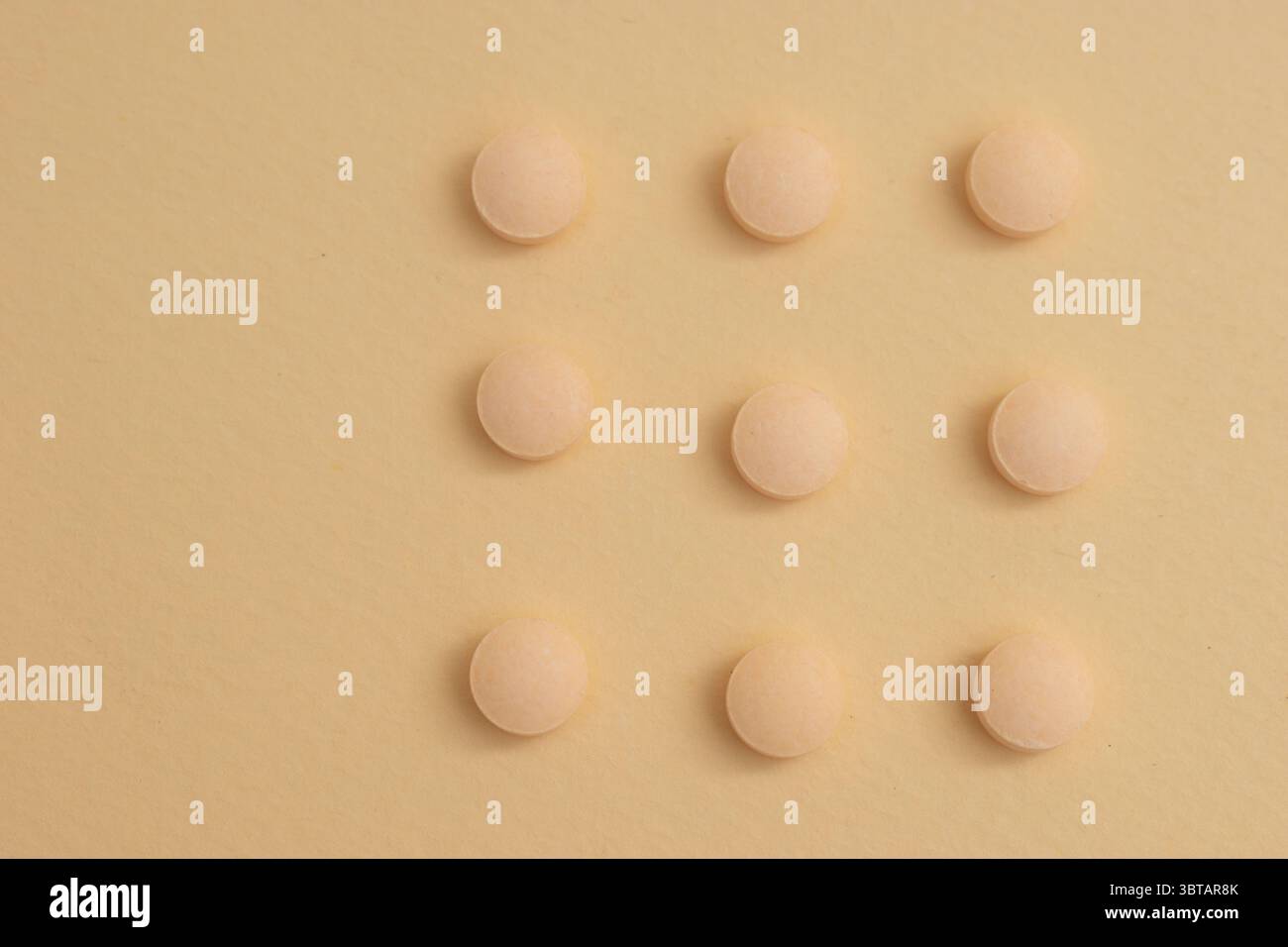 Concetto minimalista con pillole rotonde bianche in contenitore di vetro e cucchiaio su sfondo beige Foto Stock