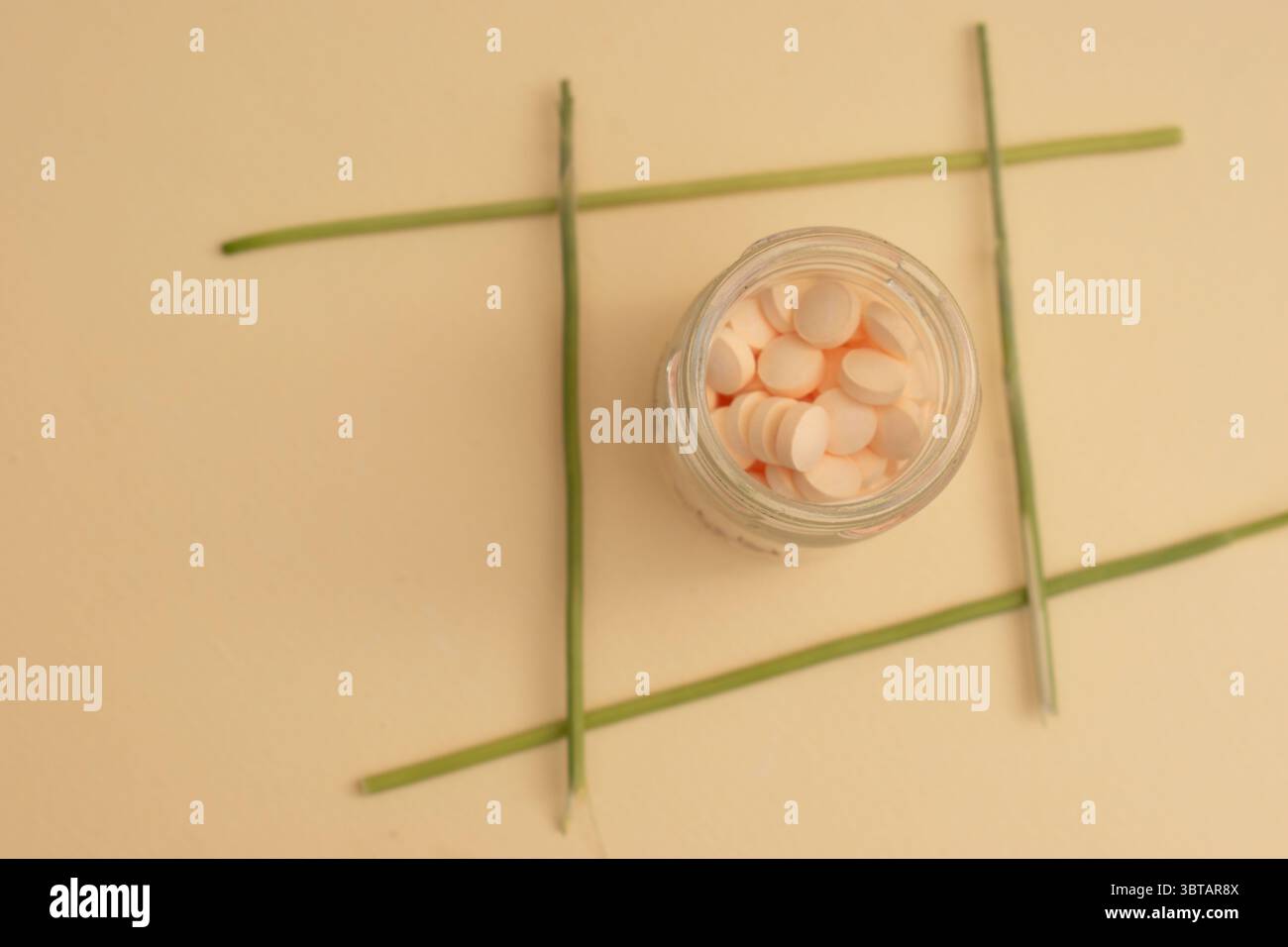 Concetto minimalista con pillole rotonde bianche in contenitore di vetro e cucchiaio su sfondo beige Foto Stock
