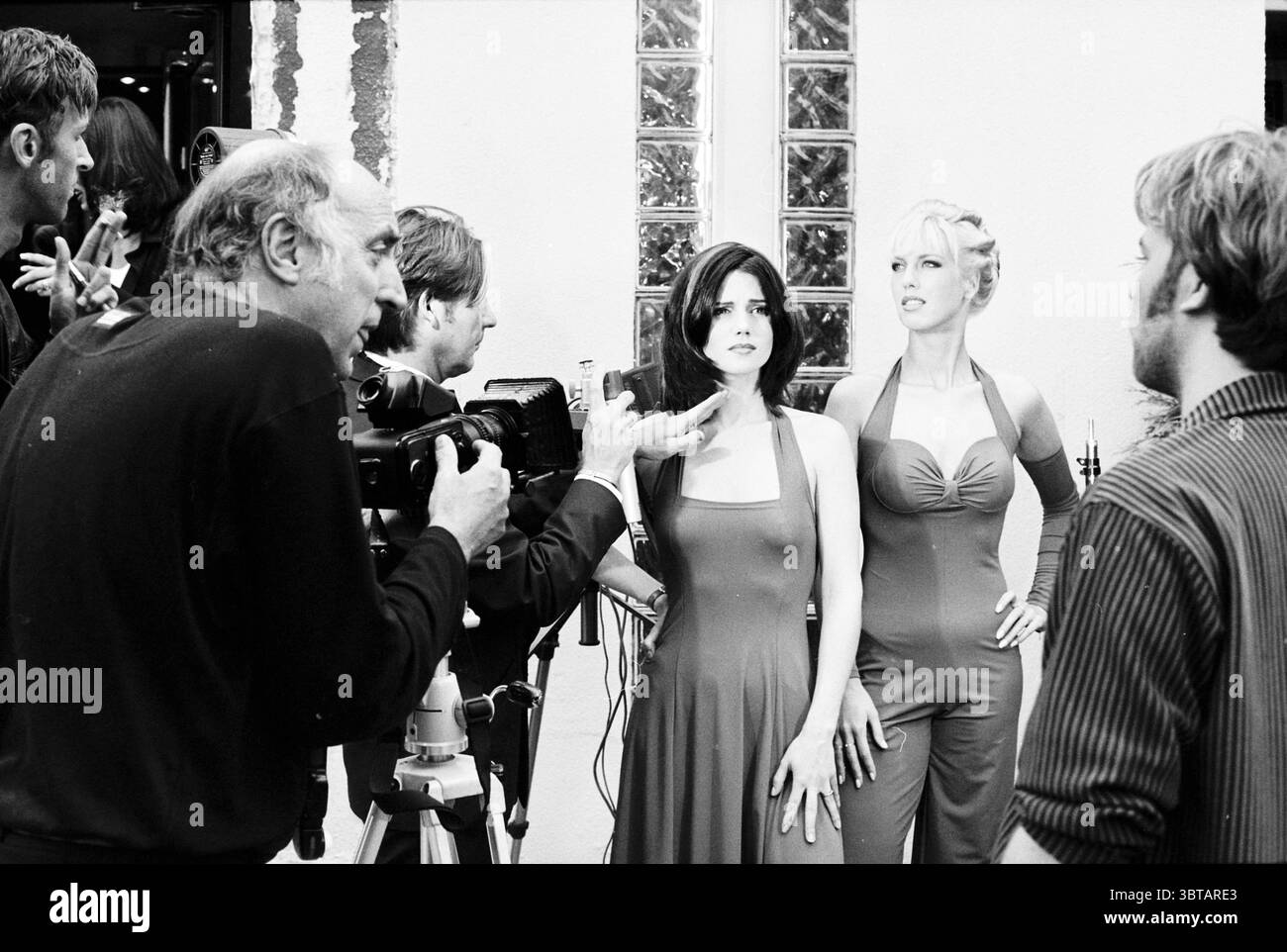Pierot parrucchiere Models IJmuiden Paesi Bassi, Whizgle News, Dutch Desk, Paesi Bassi, 1950 - 2000 on 28-09-1997. Questi sono gli elementi dell'immagine. La scena cattura un momento vivace in un ambiente creativo, probabilmente un set per un film o un servizio fotografico. Due donne stanno in primo piano, entrambe vestite con abiti eleganti e aderenti che enfatizzano le loro figure. Una donna ha lunghi capelli scuri, mentre l'altra sfoggia uno stile più leggero e duro. Le loro espressioni trasmettono fiducia, con un sottile accenno di intrighi, mentre si preparano allo sguardo della telecamera. Li circondano a. Foto Stock