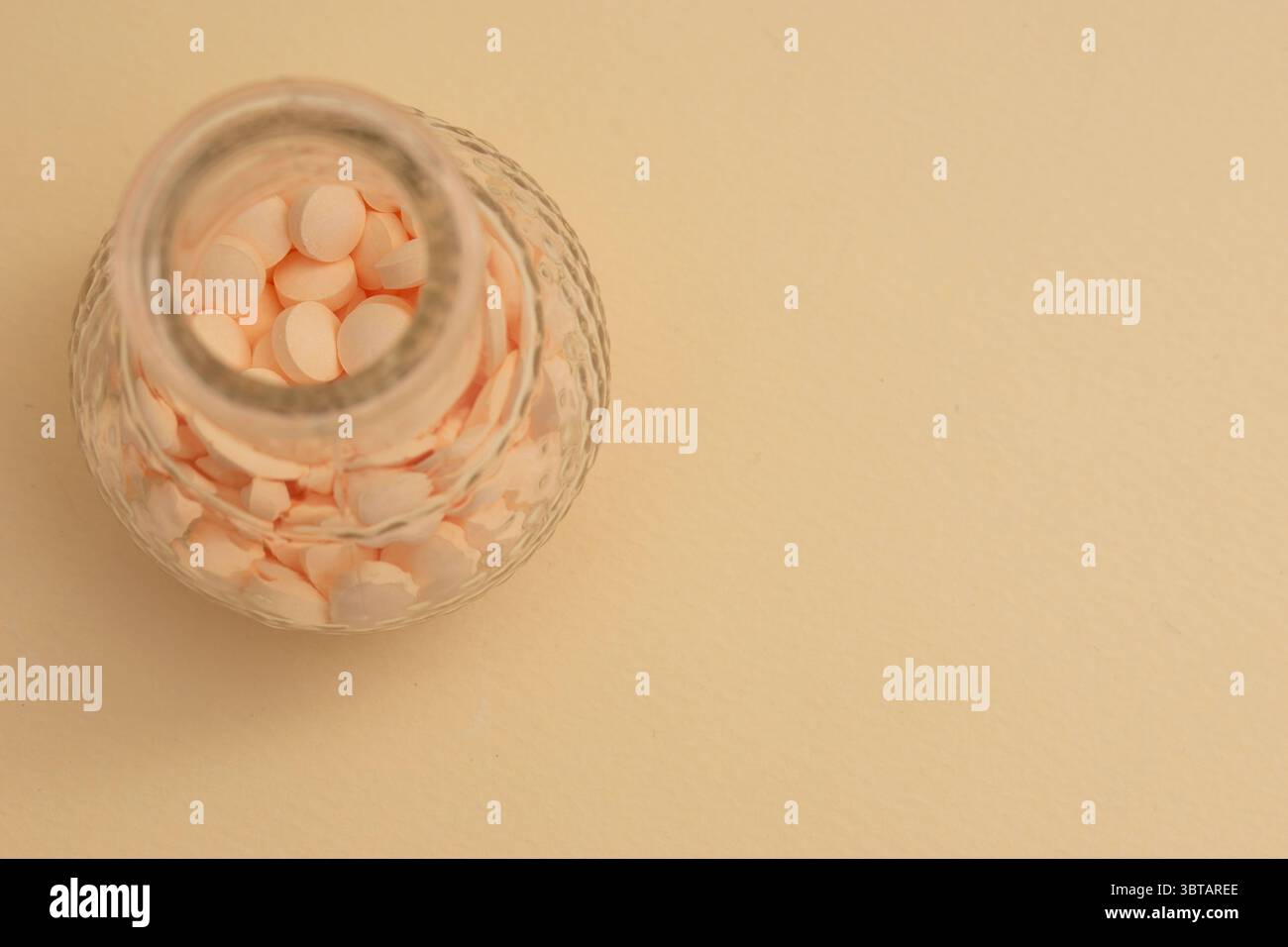 Concetto minimalista con pillole rotonde bianche in contenitore di vetro e cucchiaio su sfondo beige Foto Stock
