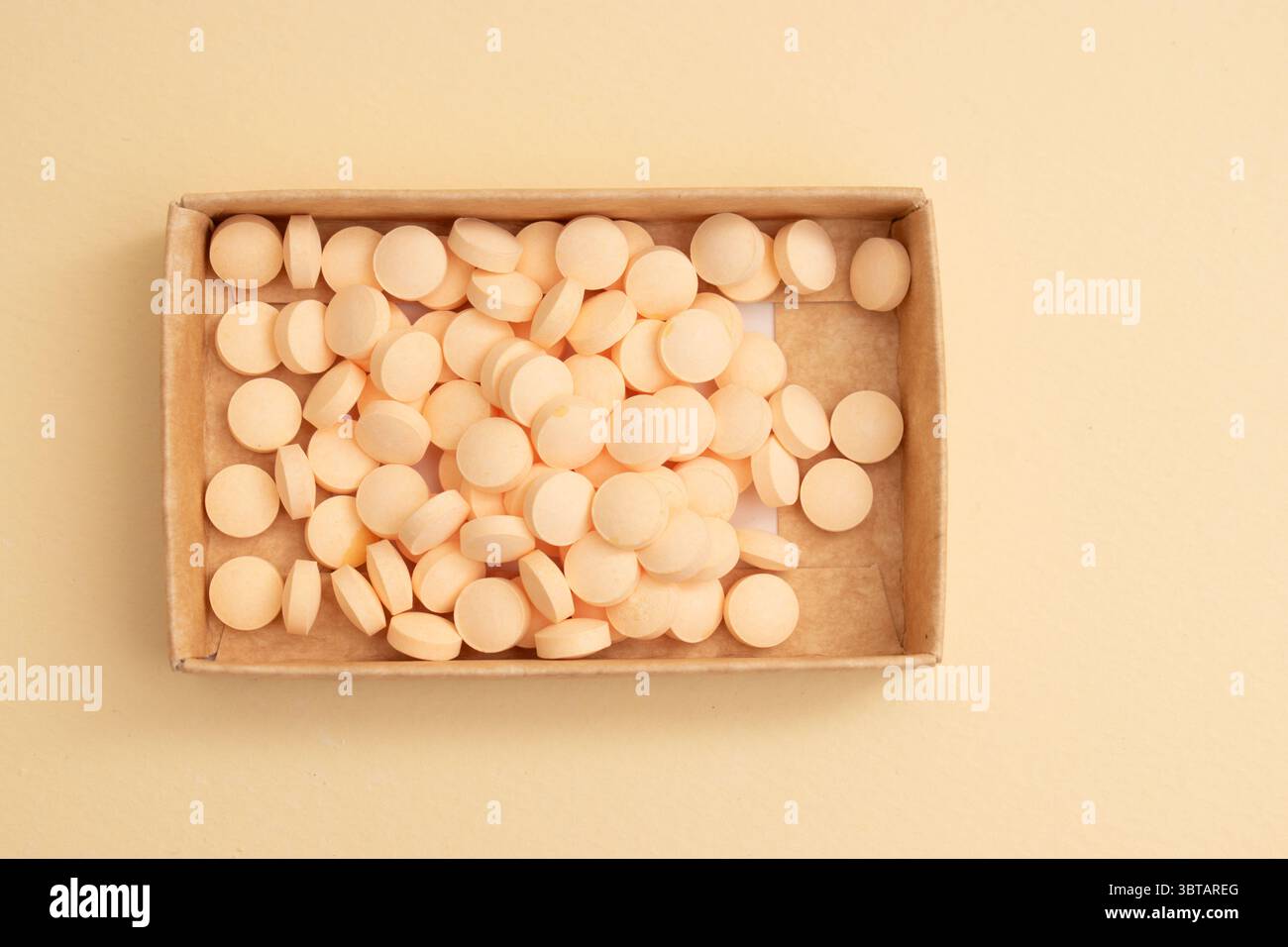 Concetto minimalista con pillole rotonde bianche in contenitore di vetro e cucchiaio su sfondo beige Foto Stock
