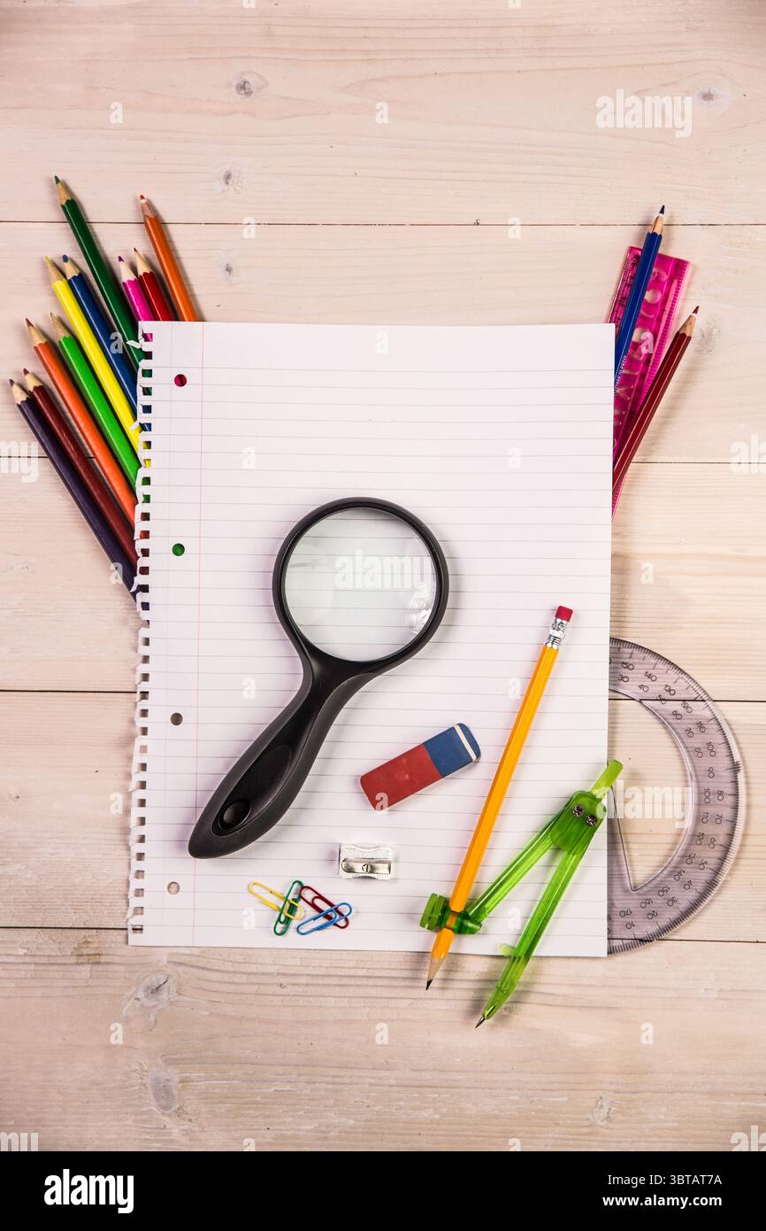 Presentazione di un notebook rivestito in bianco con design piatto su un piano portapaziente con lente di ingrandimento e strumenti di disegno Foto Stock