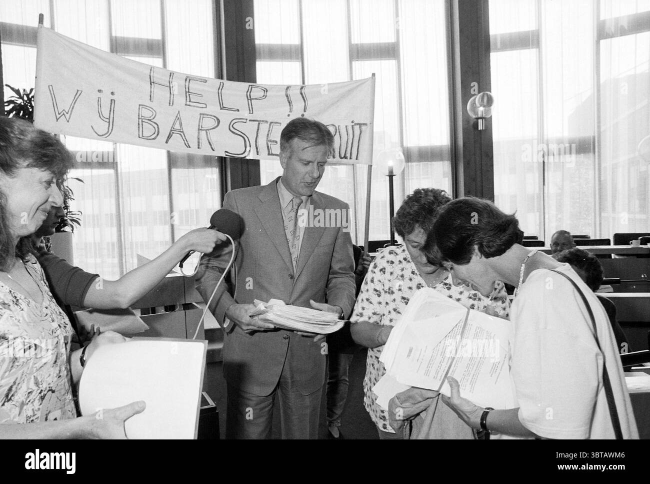 Offre autografi Rietveldschool H'dorp Hoofddorp Paesi Bassi, Whizgle News, Dutch Desk, Paesi Bassi, 1950 - 2000 il 21-08-1996. Questi argomenti vengono visualizzati nell'immagine. In uno spazioso ambiente interno caratterizzato da alti soffitti e grandi finestre che lasciano inondare la sala dalla luce naturale, un senso di urgenza permea l'atmosfera. Lo stato d'animo è teso ma fiducioso, dato che un gruppo di quattro persone si impegna in una discussione mirata. La figura prominente al centro, un uomo con un vestito di colore chiaro, tiene diversi fogli di carta in una mano. La sua espressione riflette la determinazione mentre guarda verso la t Foto Stock