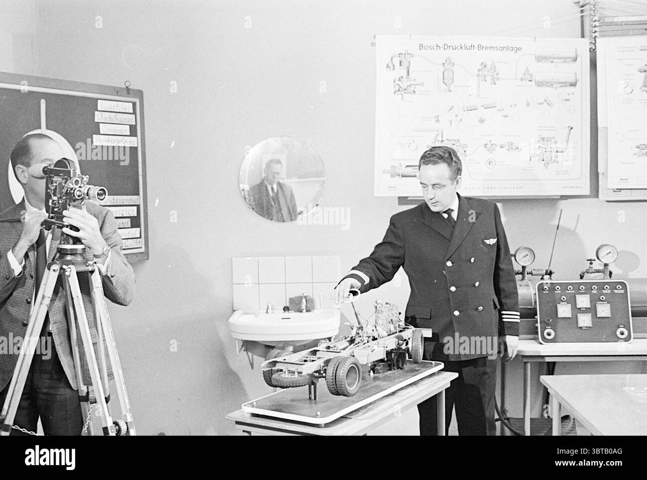 T.V. Recordings N.Z.H. Noord Zuid Hollandse Vervoersmaatschappij N.V. NZ, Whizgle News, Dutch Desk, Paesi Bassi, 1950 - 2000 il 21-03-1967. Questi argomenti vengono visualizzati nell'immagine. Nella scena, un ambiente interno ben illuminato rivela un momento focalizzato su un modello in miniatura di un componente automobilistico. Un uomo vestito con un'uniforme formale si erge accanto al modello, che sembra essere stato progettato in modo complesso, mostrando varie parti meccaniche. La sua attenzione è rivolta verso il modello, suggerendo che è in corso una spiegazione o una dimostrazione. Nelle vicinanze, un altro individuo è posizionato con una macchina fotografica d'epoca Foto Stock