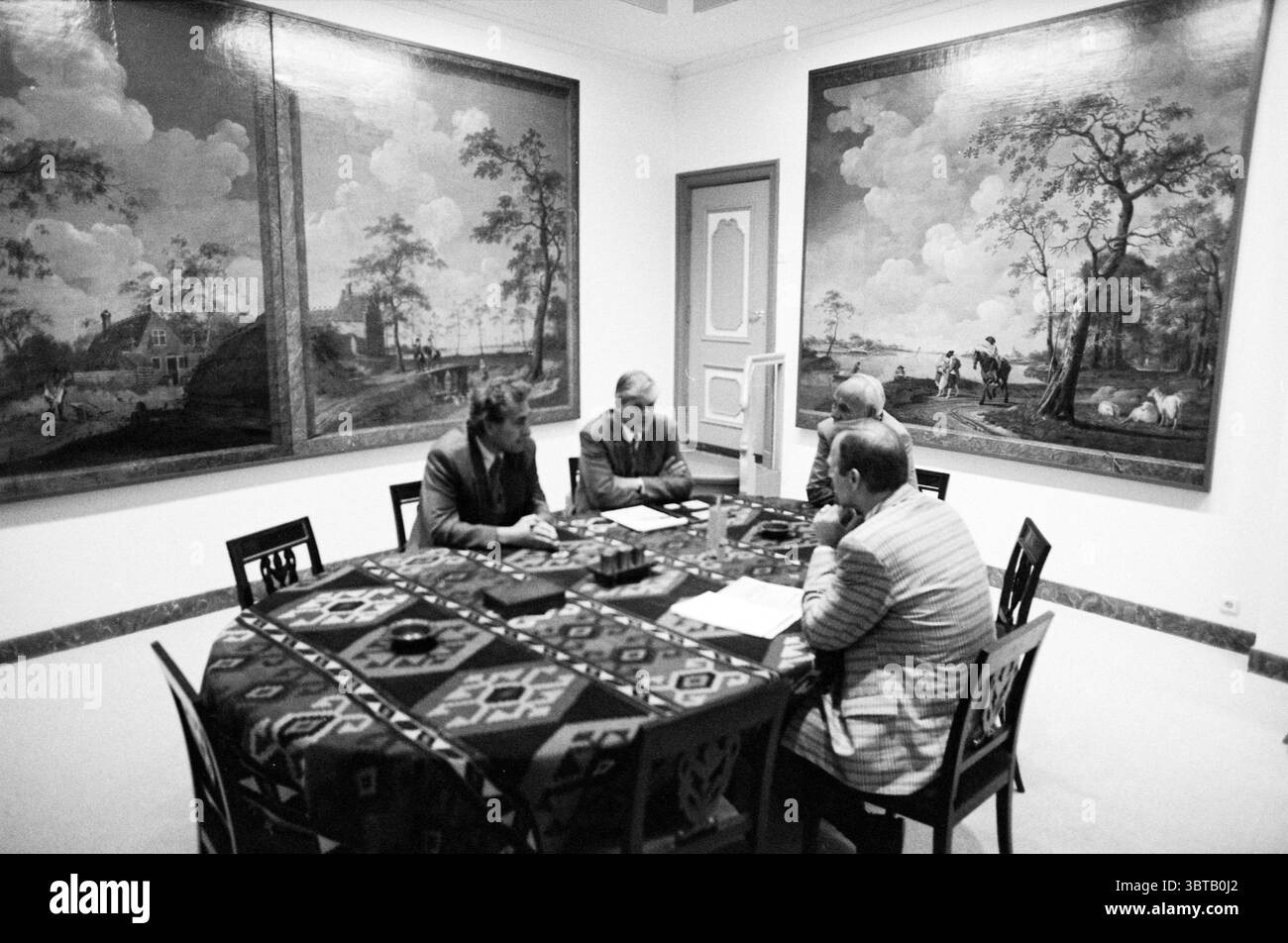 Negoziati comune di Haarlem Haarlem Paesi Bassi, Whizgle News, Dutch Desk, Paesi Bassi, 1950 - 2000 il 17-06-1992. Questi argomenti vengono visualizzati nell'immagine. La scena è ambientata in una spaziosa sala adornata con grandi dipinti ornati sulle pareti che raffigurano vasti paesaggi con dolci colline, alberi e figure impegnate in varie attività, dando un senso di tranquillità e bellezza pastorale. La tavolozza dei colori di queste opere d'arte completa i toni tenui della stanza, creando un ambiente armonioso. Al centro della scena, una tavola rotonda rivestita con una tovaglia a motivi di profondità Foto Stock