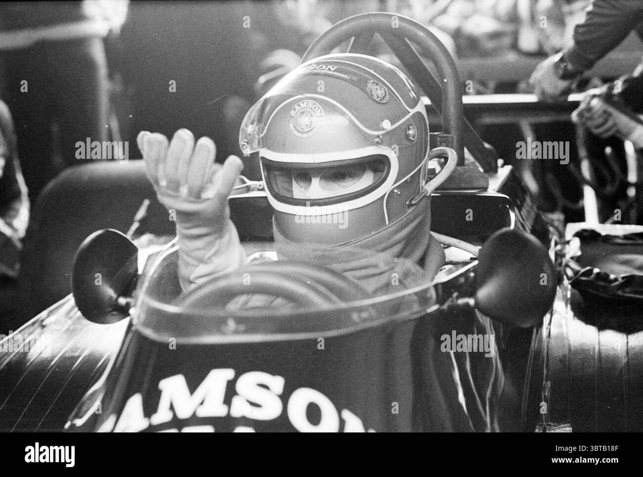 Circuito Zandvoort Zandvoort, Whizgle News, Dutch Desk, Paesi Bassi, 1950 - 2000 il 12-12-1978. Questi sono gli elementi dell'immagine. La scena cattura un pilota seduto in un'elegante auto da corsa a bordo di una cabina di pilotaggio aperta, trasudando un senso di attesa. Il conducente indossa un casco color argento lucido decorato con insegne ed emblemi, oscurando parzialmente il viso, che è concentrato e serio. La mano con i guanti viene alzata in un gesto che sembra segnalare all'equipaggio o al pubblico circostante, trasmettendo prontezza e determinazione. La vettura da corsa vanta una finitura lucida, prevalentemente nera Foto Stock