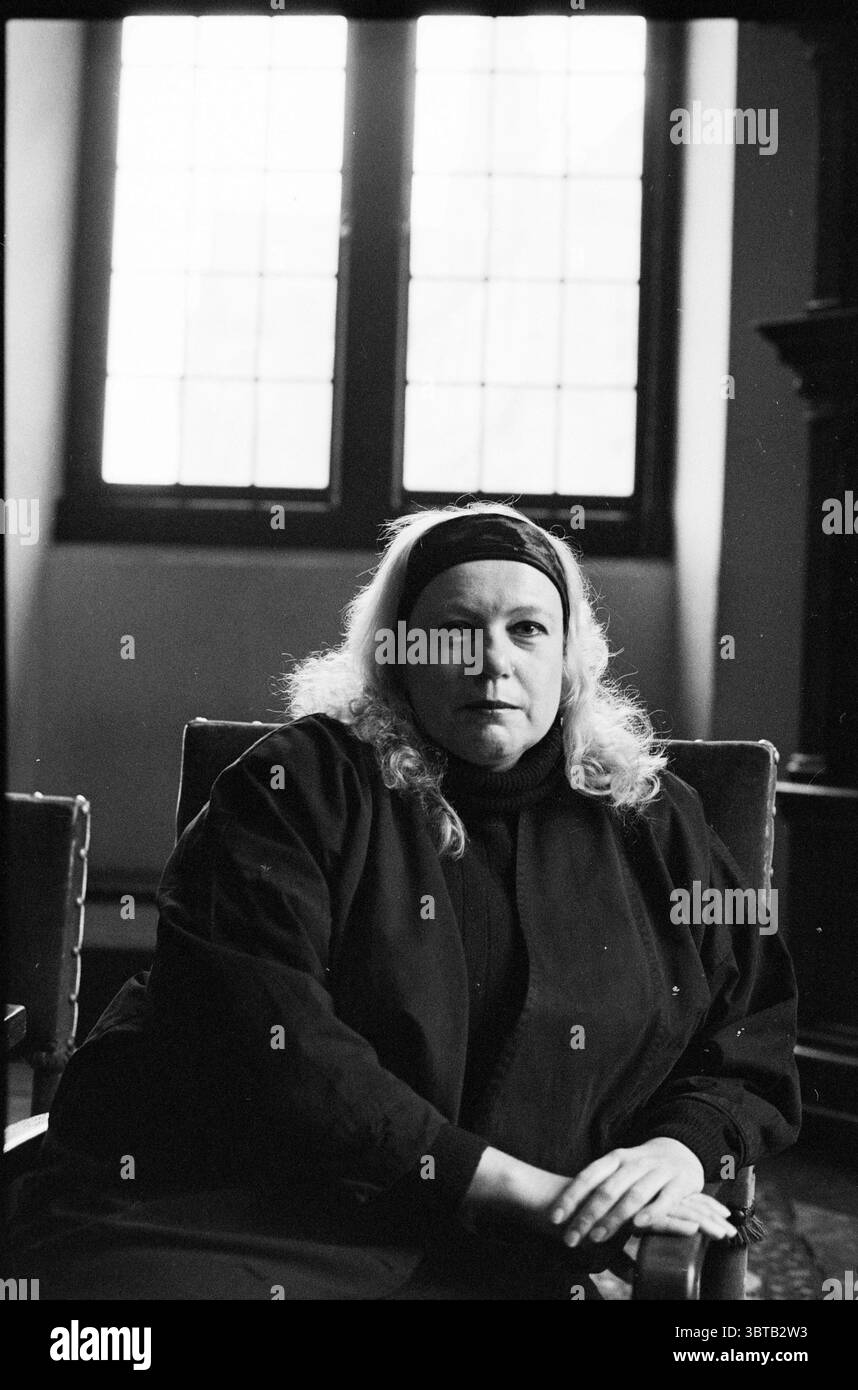 J. van de Moeren de Men, Whizgle News, Dutch Desk, Paesi Bassi, 1950 - 2000 il 10-12-1992. L'immagine include questi argomenti. La scena vede una donna seduta in una sala ben illuminata con grandi finestre a più pannelli che consentono una luce naturale soffusa di filtrare. Cattura l'attenzione con la sua espressione seria, osservando direttamente la prospettiva dello spettatore. I suoi capelli sono di colore chiaro, cadono giù tra le onde morbide intorno alle sue spalle, e indossa un capo scuro e oversize che aggiunge alla sua presenza dominante. L'ambiente ha un'aria di eleganza, con ricche texture evidenti nei mobili in legno e in Foto Stock J. van de Moeren de Men, Whizgle News, Dutch Desk, Paesi Bassi, 1950 - 2000 il 10-12-1992. L'immagine include questi argomenti. La scena vede una donna seduta in una sala ben illuminata con grandi finestre a più pannelli che consentono una luce naturale soffusa di filtrare. Cattura l'attenzione con la sua espressione seria, osservando direttamente la prospettiva dello spettatore. I suoi capelli sono di colore chiaro, cadono giù tra le onde morbide intorno alle sue spalle, e indossa un capo scuro e oversize che aggiunge alla sua presenza dominante. L'ambiente ha un'aria di eleganza, con ricche texture evidenti nei mobili in legno e in Foto Stock