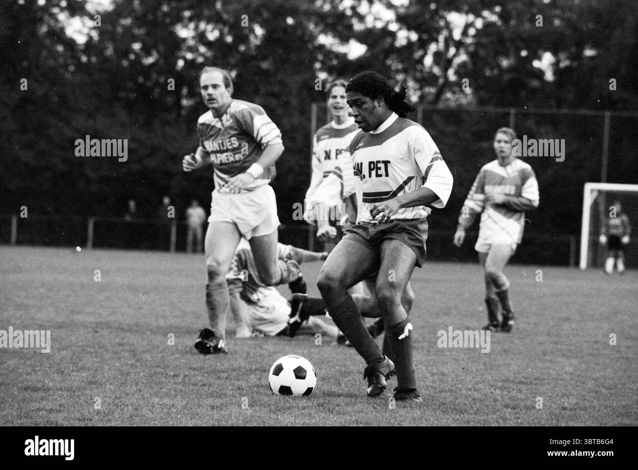 Football nuovo. Vennep - SP Woude, Whizgle News, Dutch Desk, Paesi Bassi, 1950 - 2000 il 19-10-1991. L'immagine mostra questi argomenti. La scena cattura un momento dinamico su un campo erboso, dove è in gioco una partita di calcio. In primo piano, un giocatore con un'espressione determinata controlla sapientemente la palla ai suoi piedi. Indossano una maglia bianca e rossa, in contrasto vivo con il verde intenso dell'erba. I capelli del giocatore sono corti, aggiungendo un senso di agilità al loro aspetto. Attorno a questa figura centrale ci sono diversi altri giocatori, ciascuno impegnato in pose diverse che trasmettono il mot Foto Stock