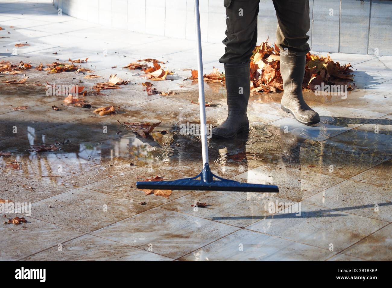 Pulire una superficie in autunno con foglie cadute e acqua Foto Stock