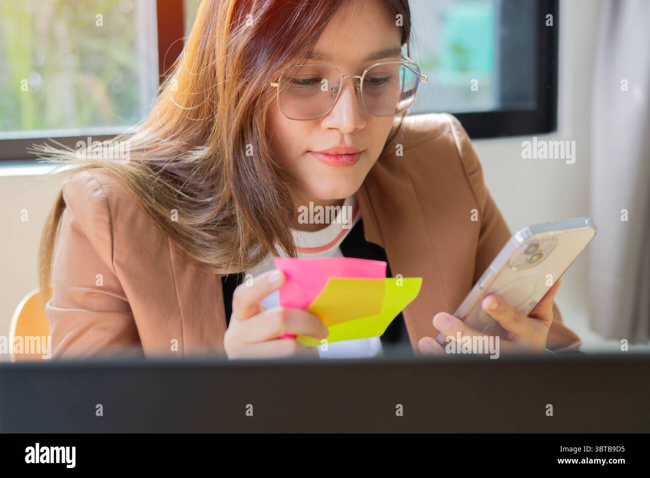 Donna d'affari professionale asiatica di successo dipendente in tuta formale seduta sorridente alla scrivania della postazione di lavoro con computer Foto Stock