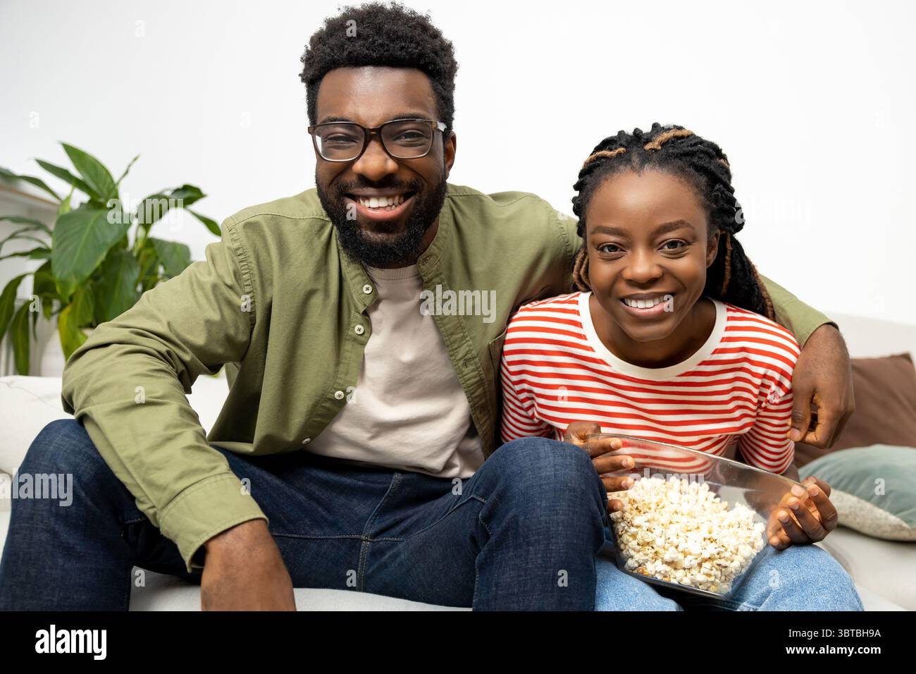 Giovane coppia che mangia popcorn e guarda la tv a casa Foto Stock
