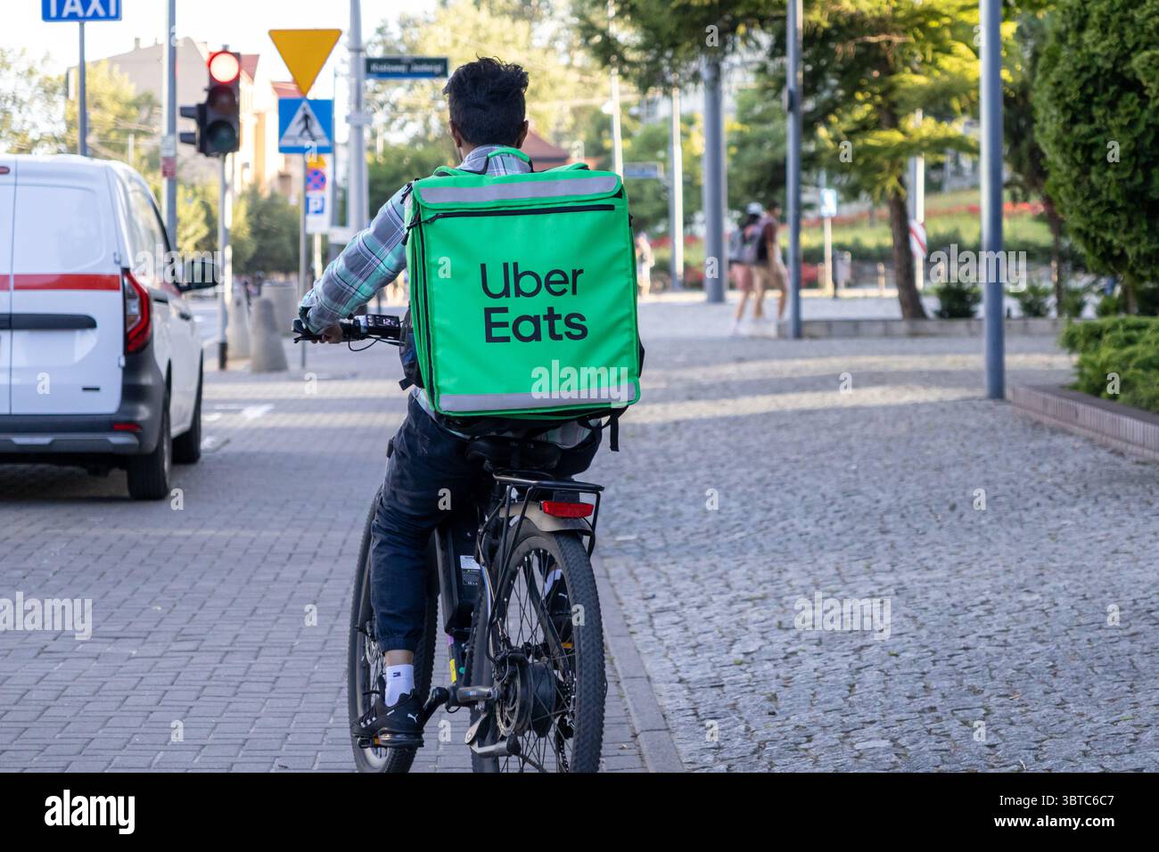 Poznan, Polonia - 30 giugno 2025: Borsa a marchio Uber Eats trasportata da un corriere in bicicletta, pronta a consegnare i pasti in un paesaggio urbano attivo Foto Stock