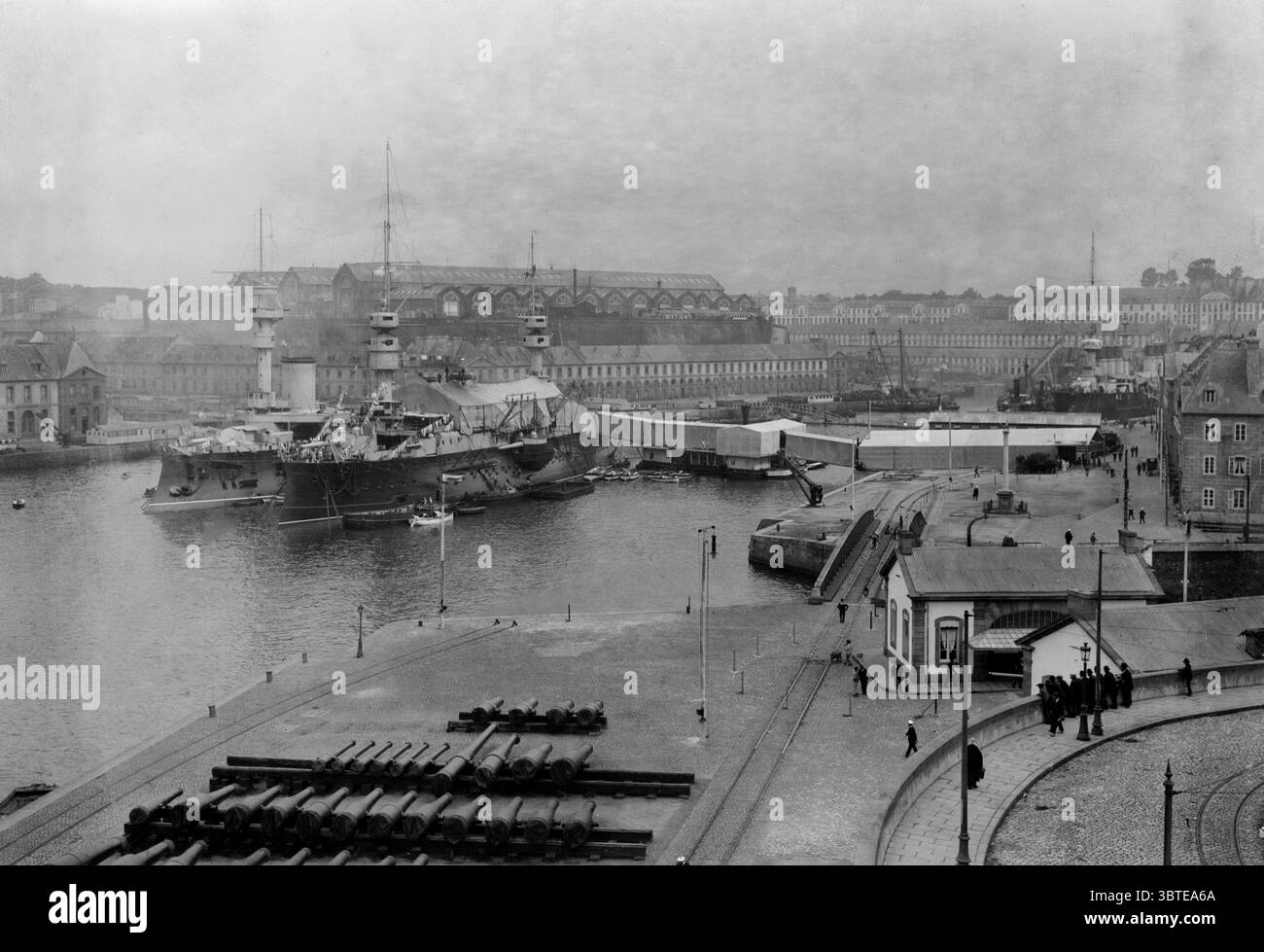 Base navale francese a Brest in Bretagna , che mostra il cantiere navale con navi da guerra ormeggiate e con nuovi barili di cannoni impilati sul lato . Primi anni '1900 Foto Stock