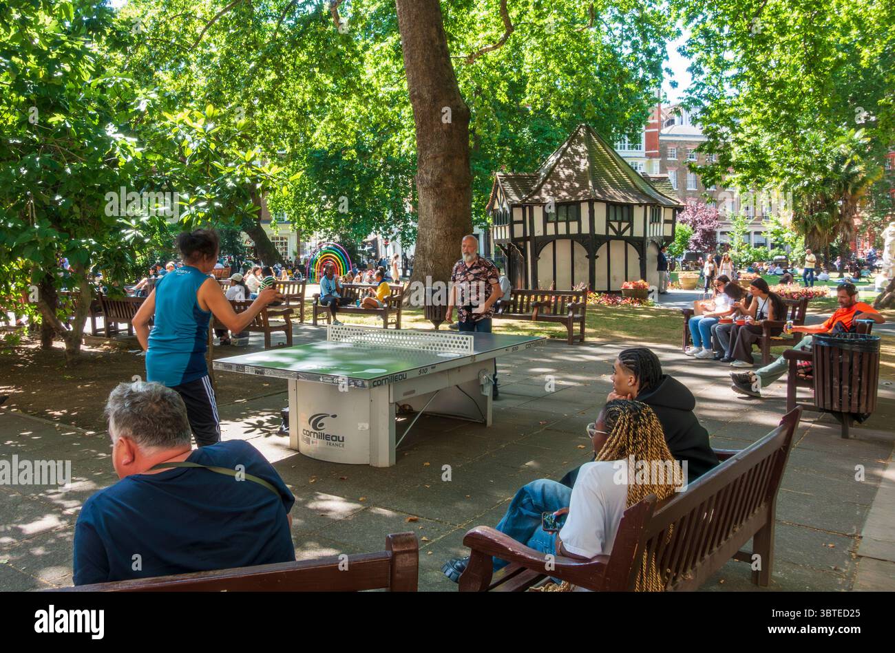 Persone che giocano a ping pong e si rilassano in Soho Square in estate, nel centro di Londra Foto Stock