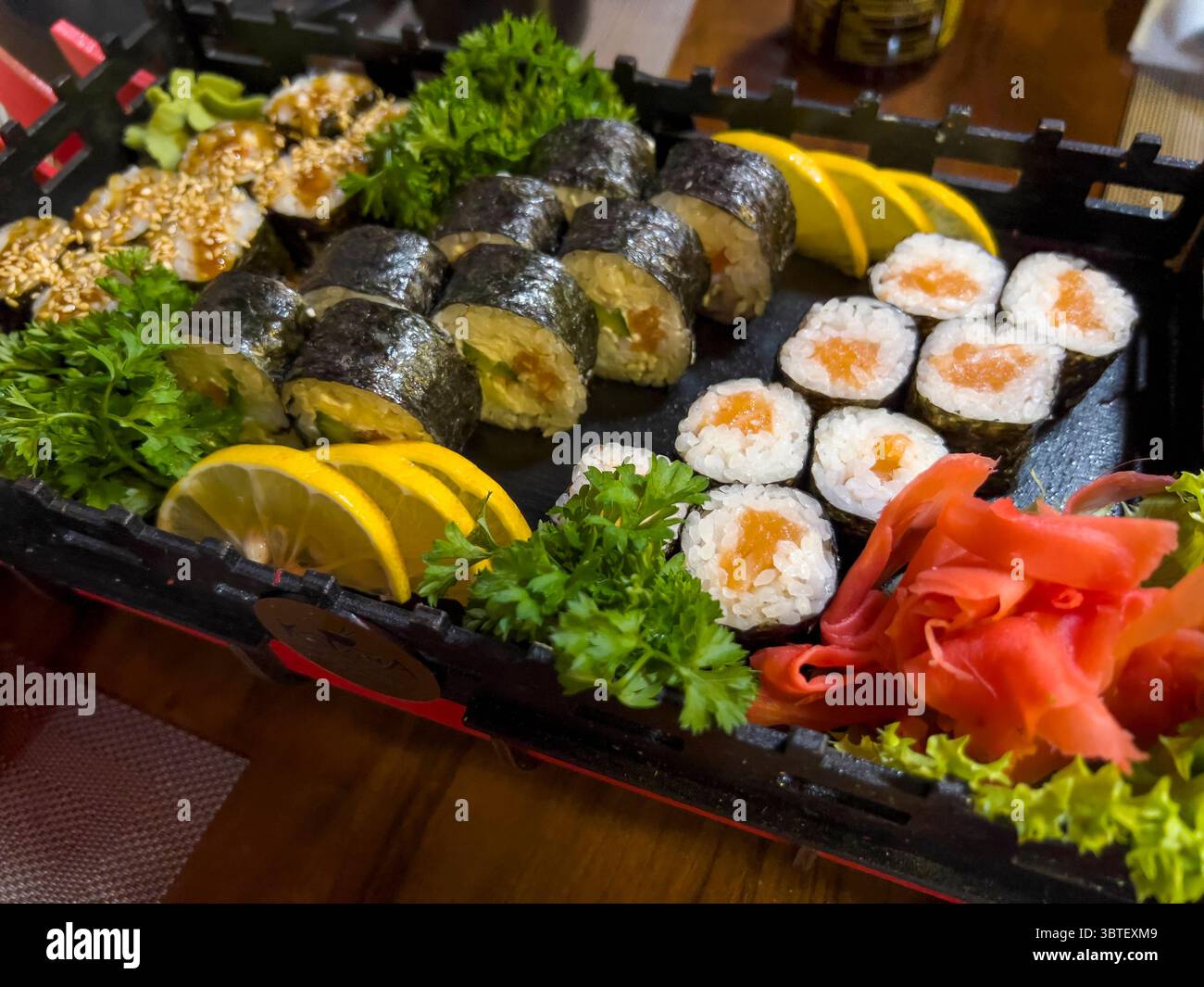 Panini di sushi guarniti con erbe fresche e fette di limone, che offrono una fusione di sapori e una presentazione vivace. Foto Stock