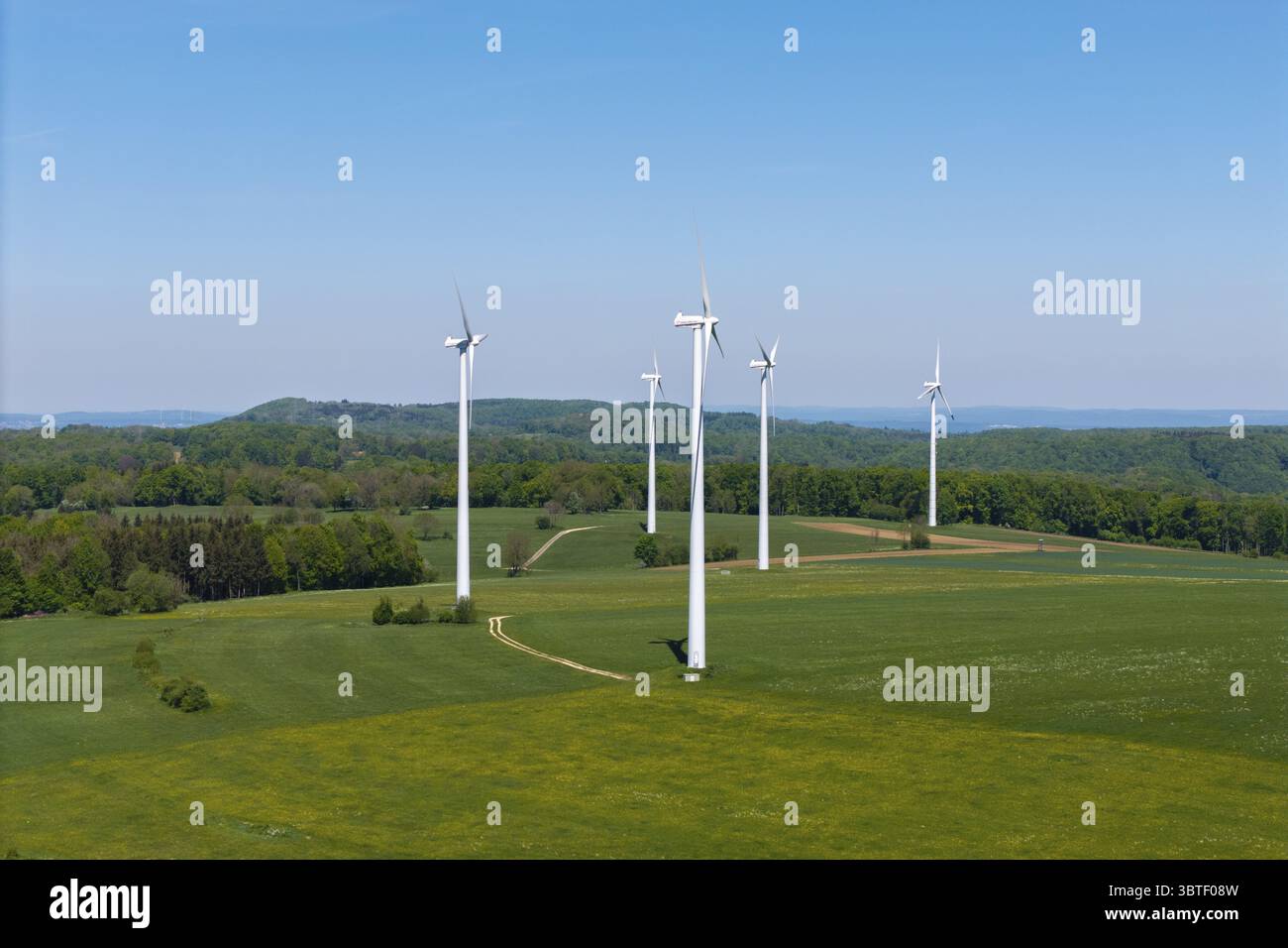 Fila di generatori eolici su un paesaggio ondulato con cielo limpido, Swabian Alb, Baden-Wuerttemberg, Germania Foto Stock