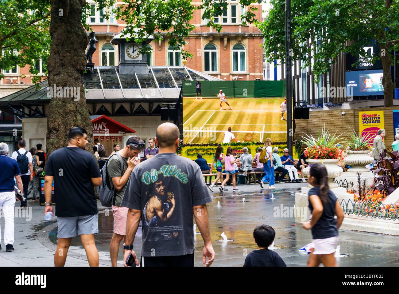 Persone che guardano il tennis da Wimbledon su un grande schermo a Leicester Square, nel centro di Londra. Foto Stock