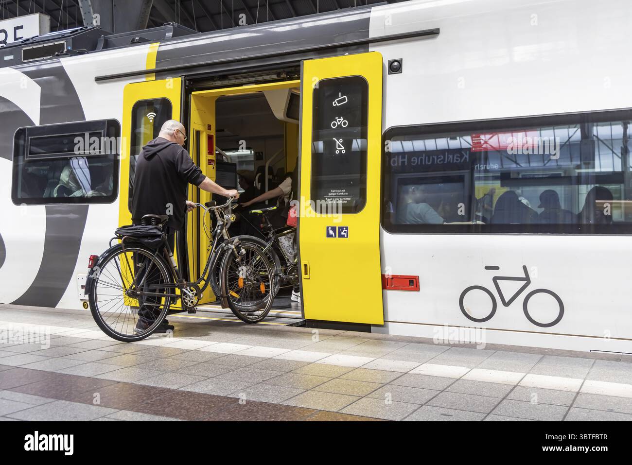 Piattaforma con viaggiatori e biciclette davanti al vano biciclette. Stazione centrale con S-Bahn a Karlsruhe, Baden-Wuerttemberg, Germania Foto Stock