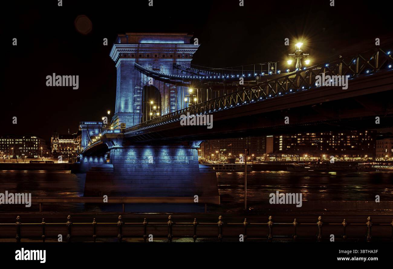 Iconico Ponte delle catene illuminato in blu sul Danubio di notte, monumento storico e vista panoramica di Budapest, Ungheria, marzo 2025 Foto Stock