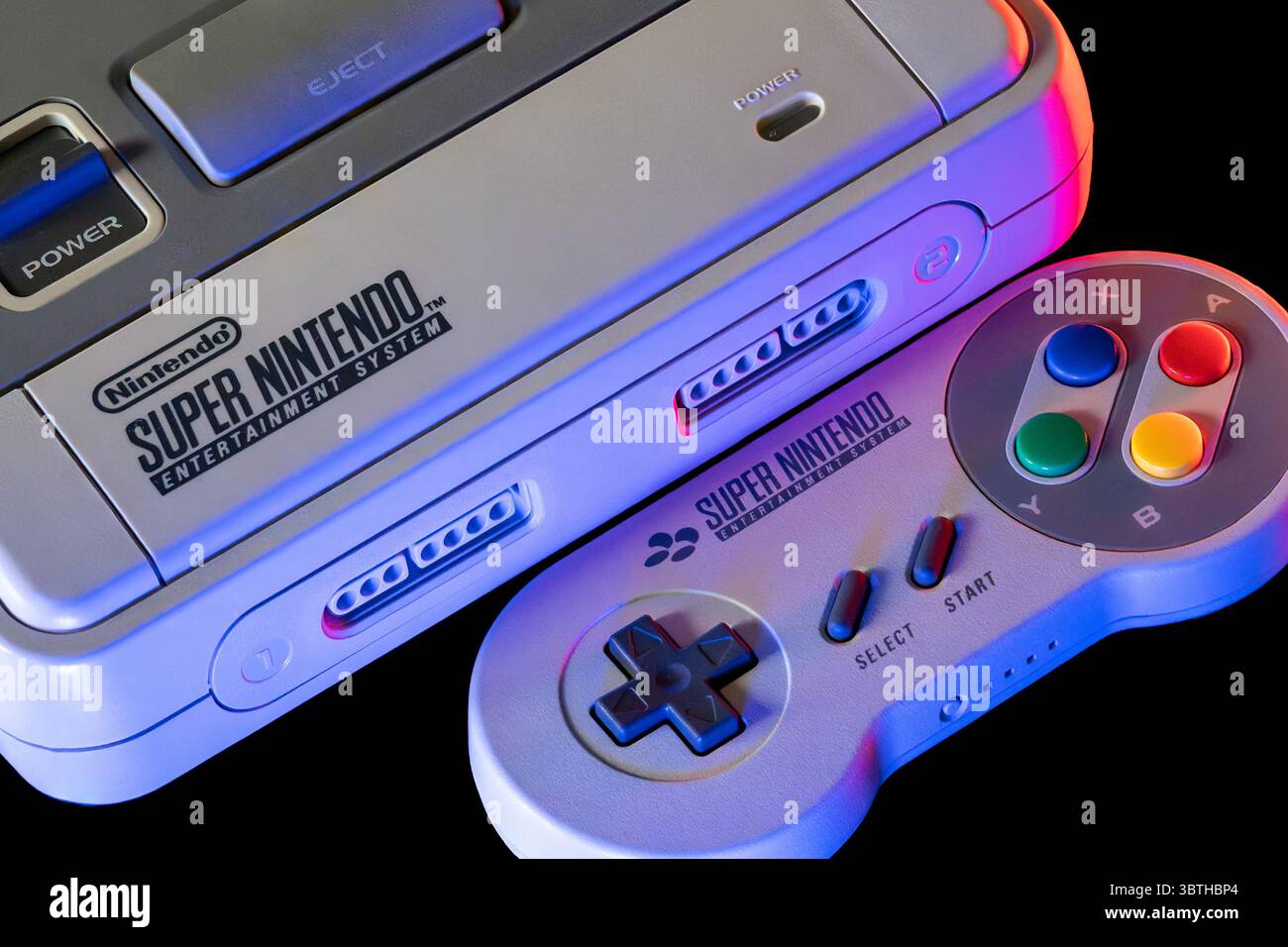 Console SNES con moderno controller wireless, ripresa con illuminazione da studio. Hardware di gioco classico retrò dei primi anni '1990 Foto Stock